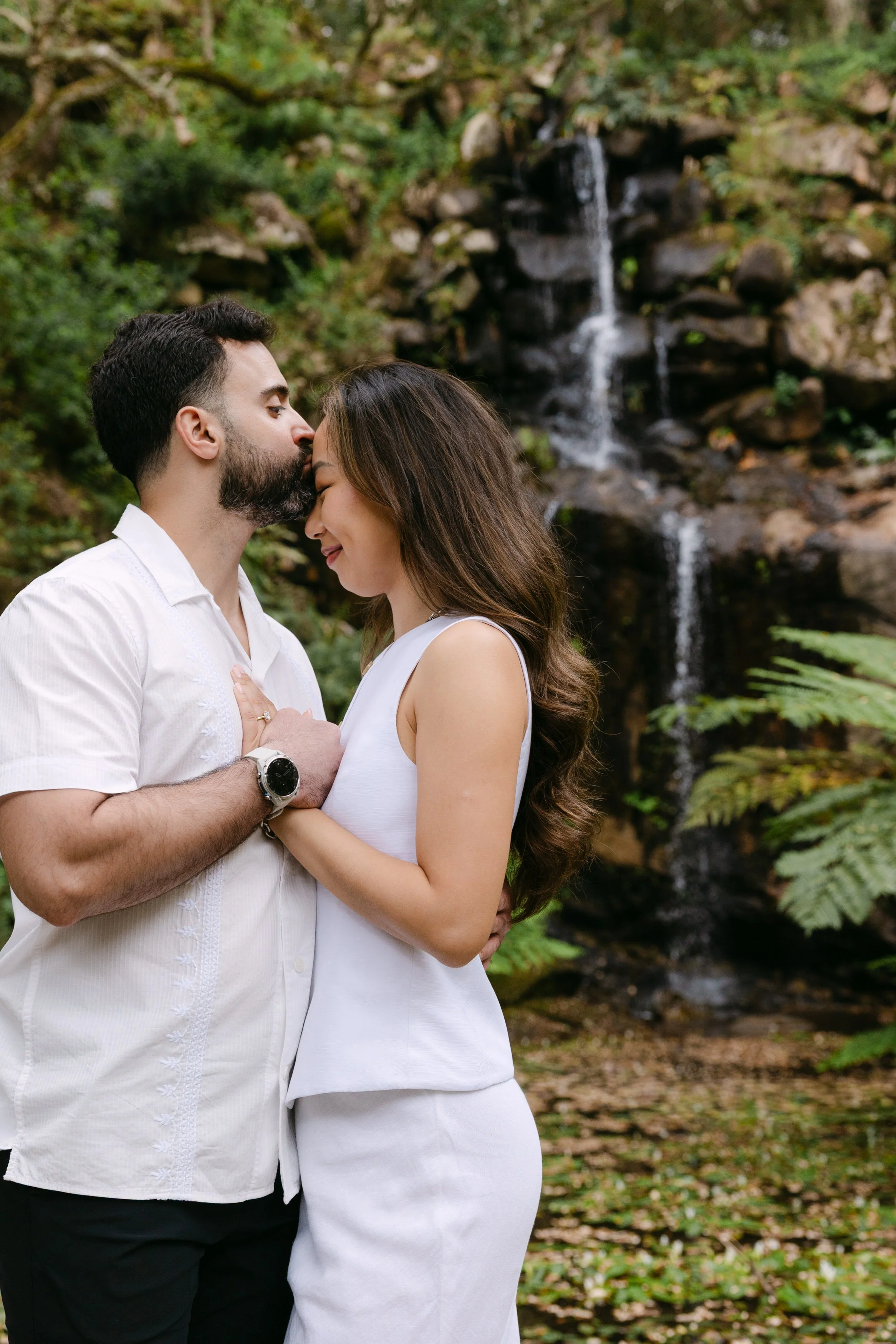 Romantic close-up portrait of engaged couple beside waterfall at Monserrate gardens in Sintra.