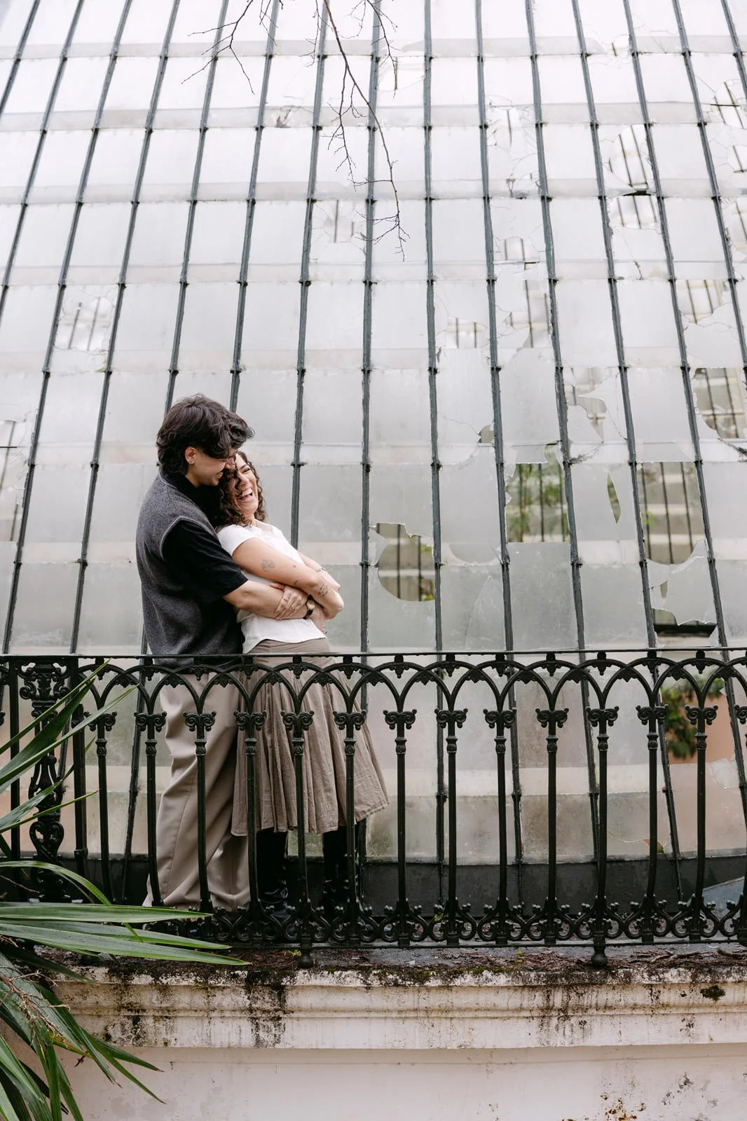 Couple embracing beside the iconic greenhouse at Tapada das Necessidades during an engagement session