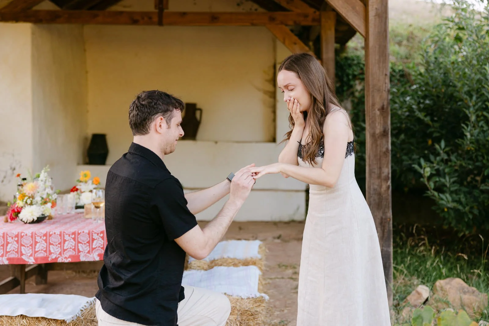 Newly engaged couple smiling as he places the engagement ring on her finger after a surprise proposal at Quinta de Sant’Ana.