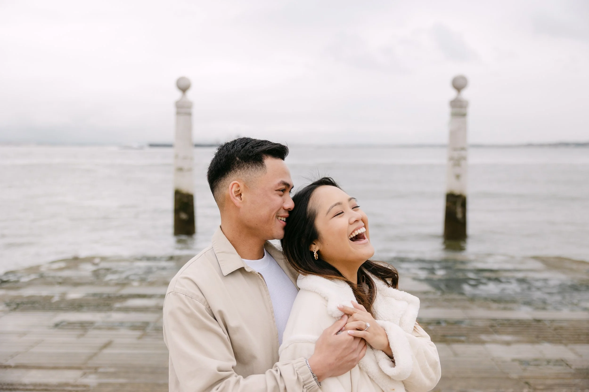 Couple laughing together at Cais das Colunas during an engagement photoshoot in Lisbon, Portugal.