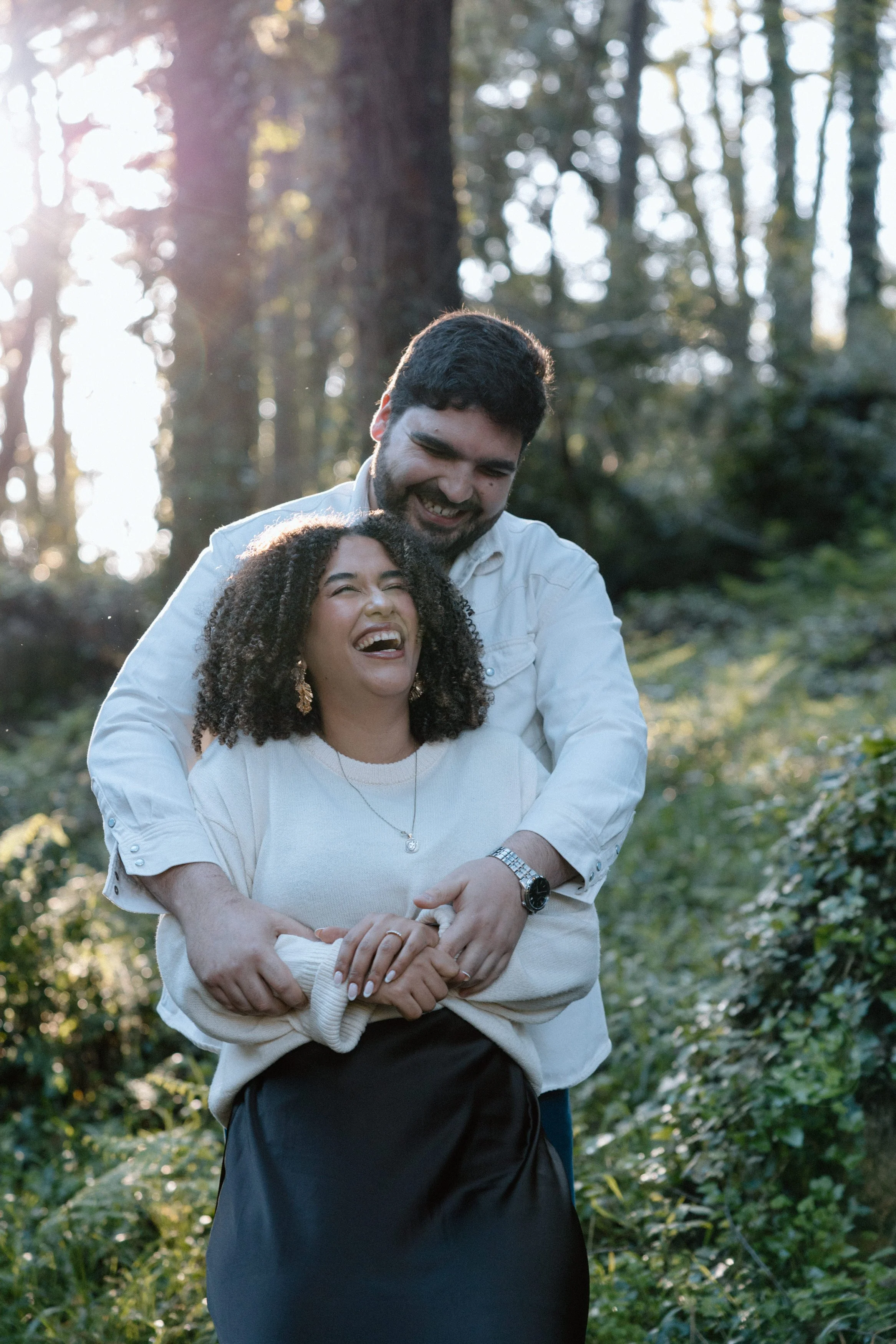 Playful engagement session in Sintra with couple embracing in forest