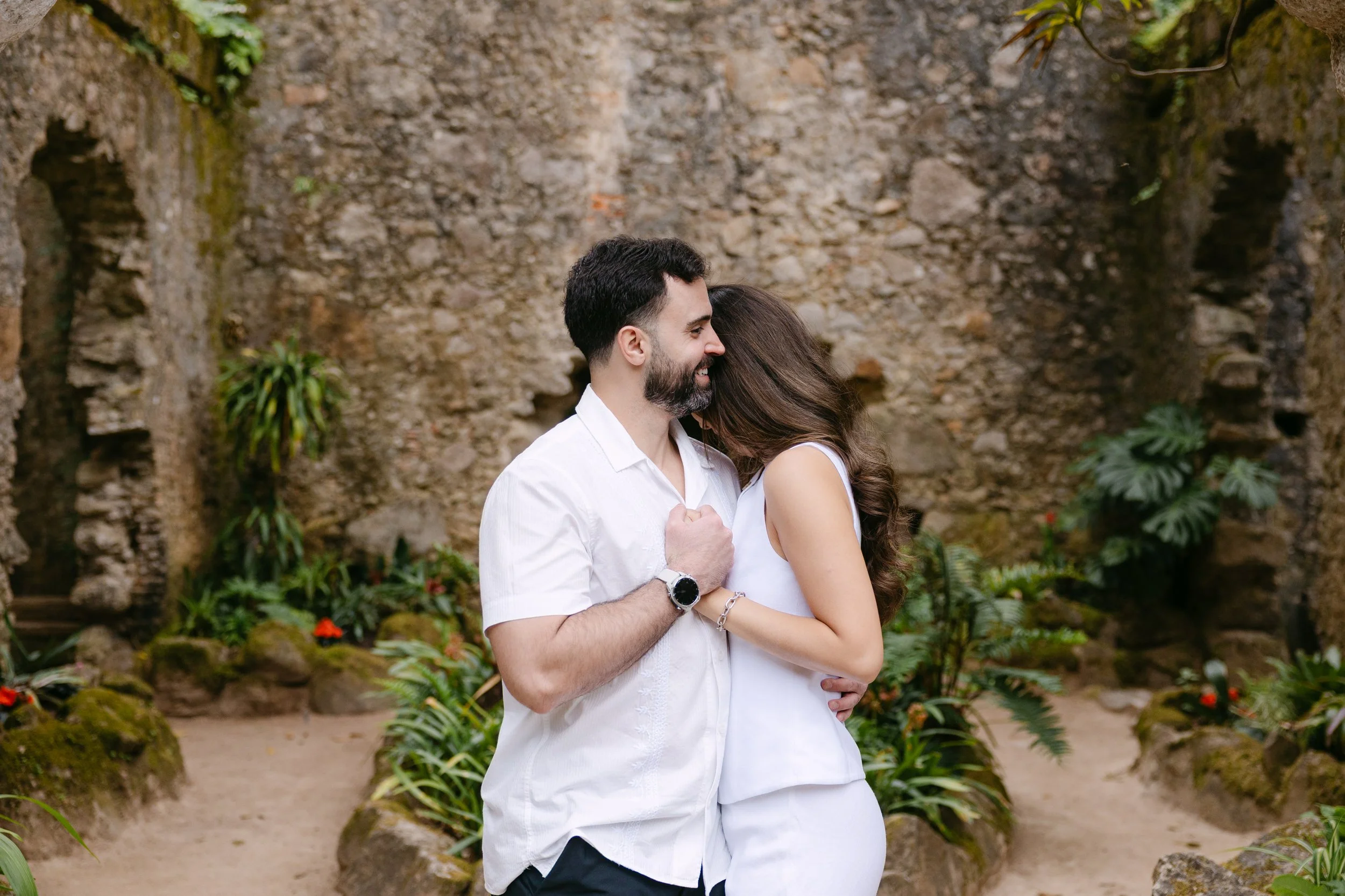 Newly engaged couple embracing during a romantic proposal photoshoot at Monserrate in Sintra.