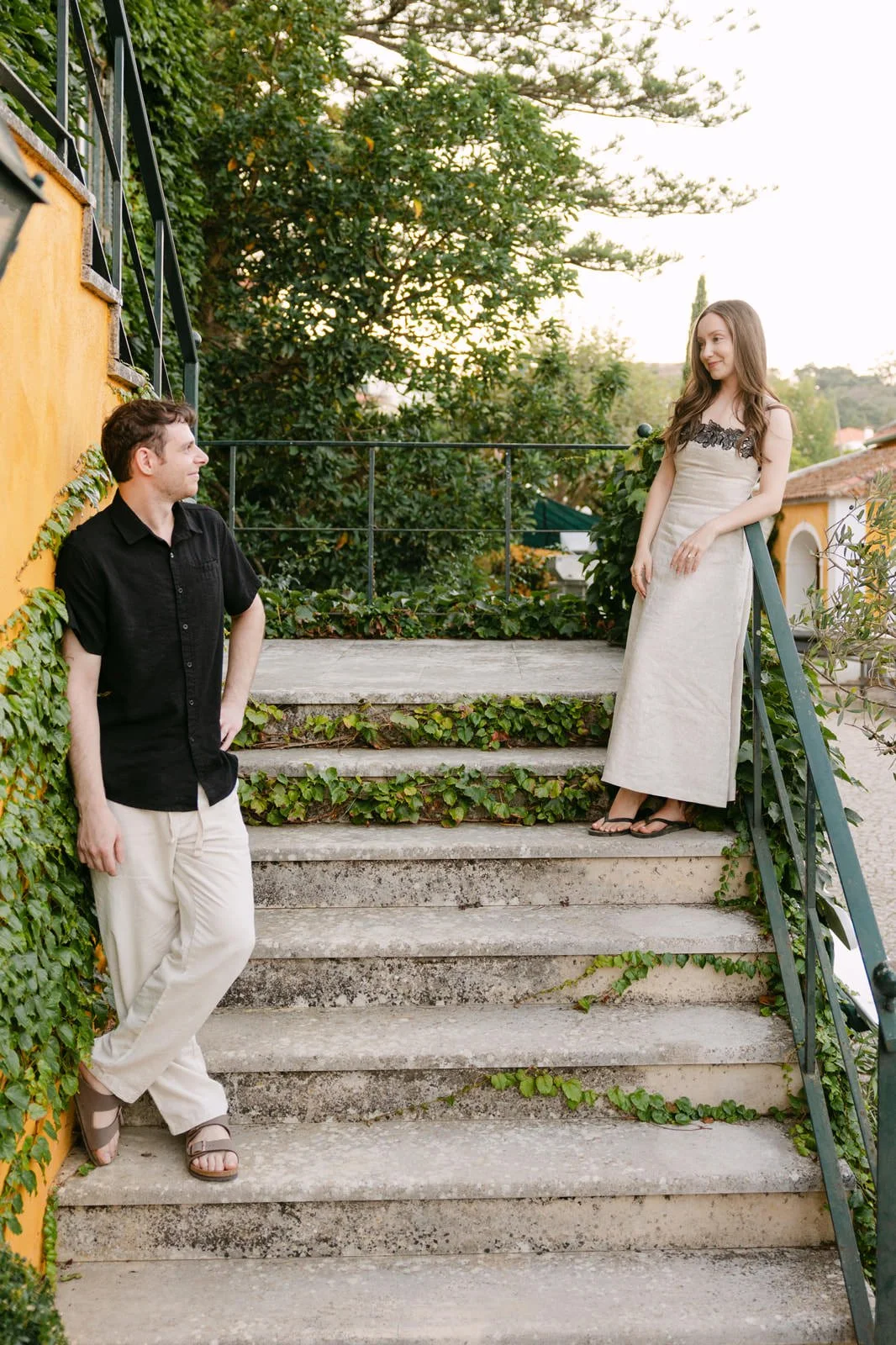 Newly engaged couple sharing a playful moment on the stone steps at Quinta de Sant’Ana during their engagement session in Portugal.