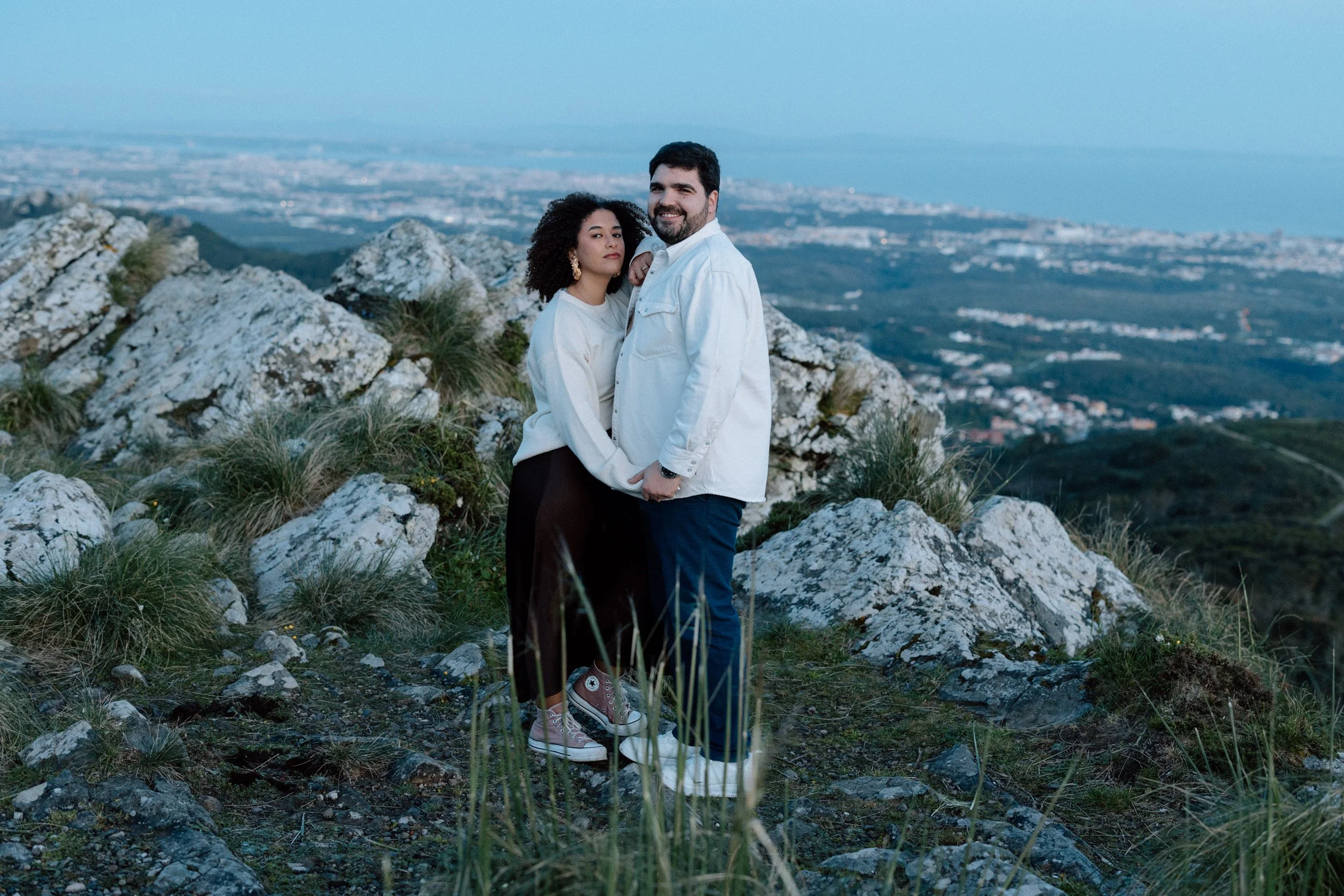 Couple standing together on rocky cliffs during engagement session in Sintra Portugal