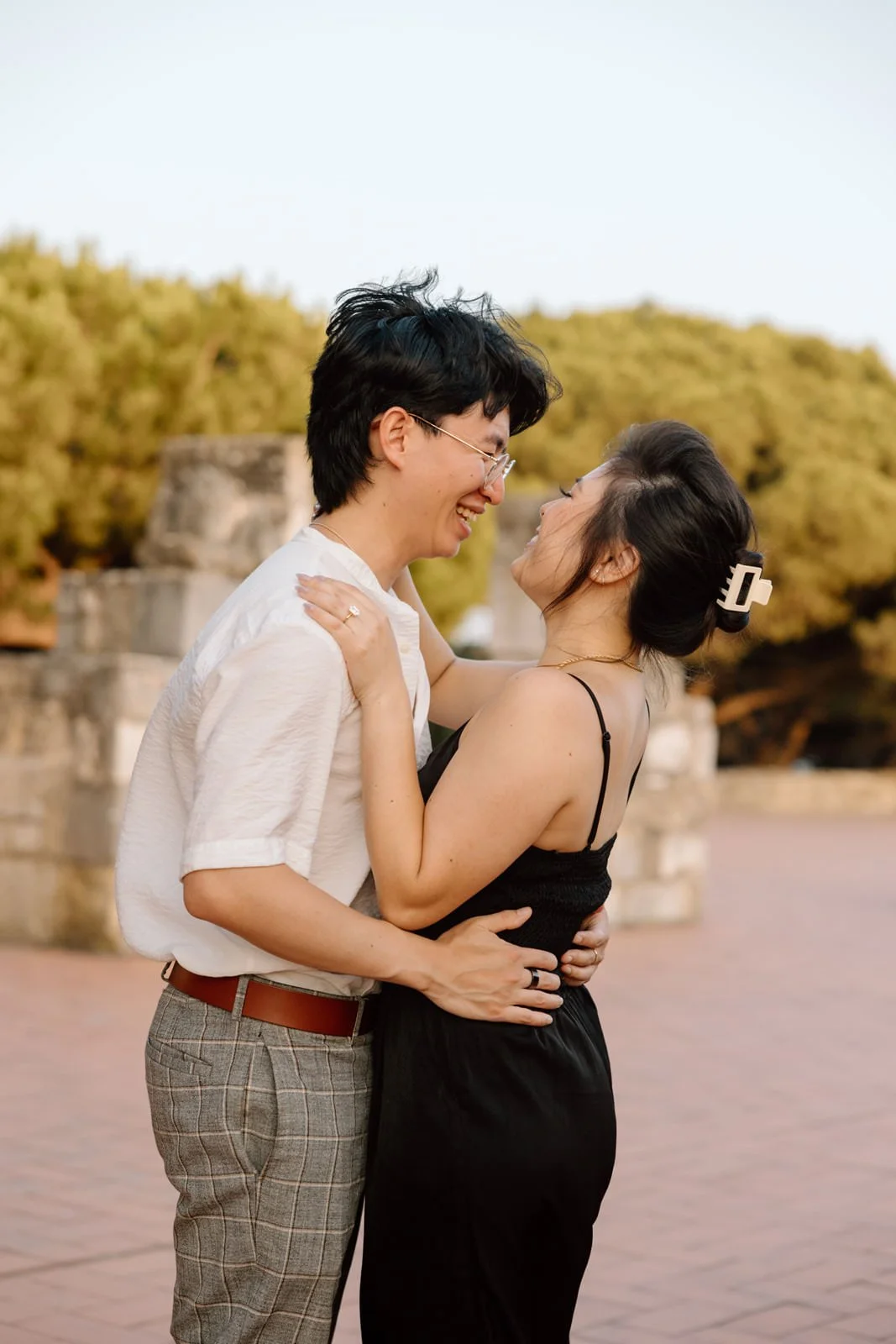 Recently engaged couple laughing together during a romantic engagement session at Castelo de São Jorge overlooking Lisbon.