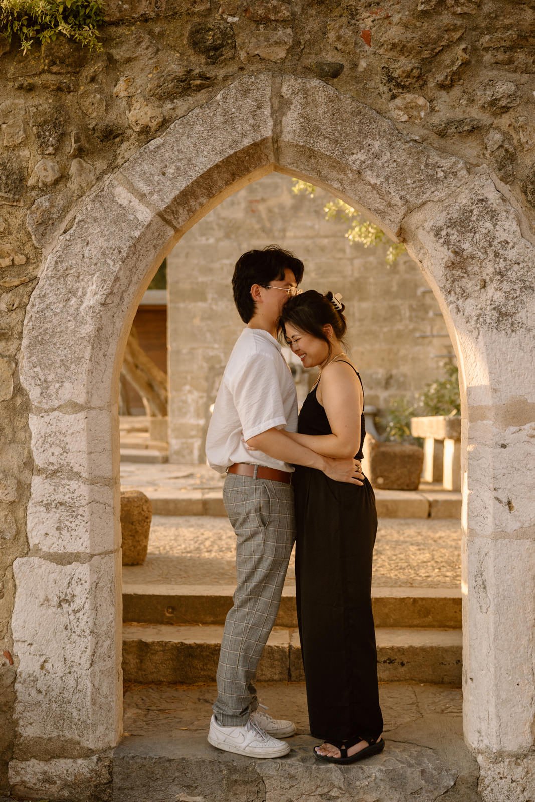 Couple sharing a quiet moment beneath one of the historic arches inside Castelo de São Jorge during a Lisbon engagement session.