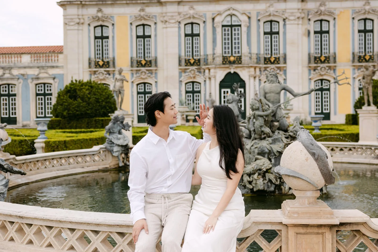Engaged couple posing in front of the fountain at Palácio de Queluz, Portugal.