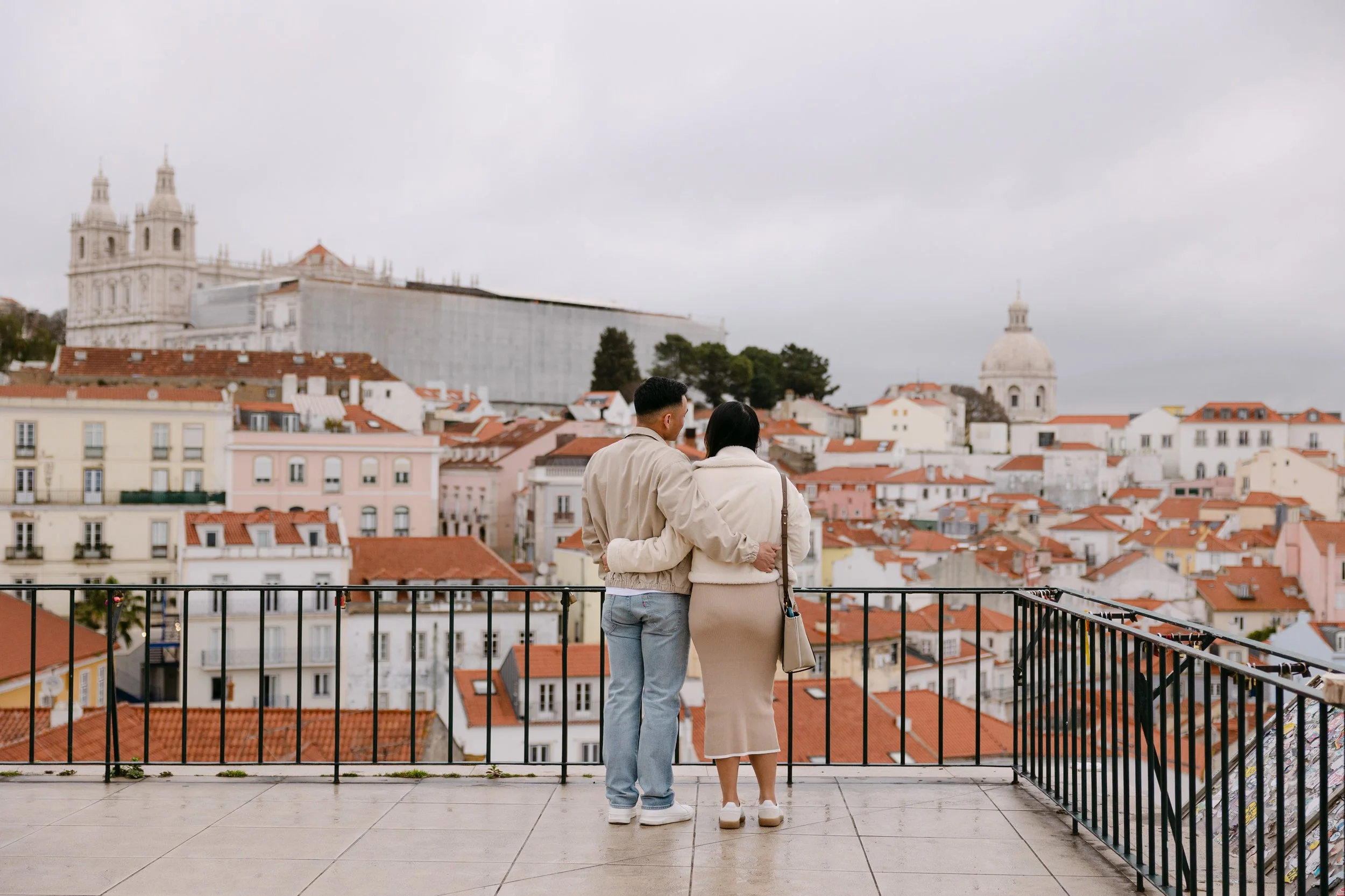 Couple overlooking Lisbon at Miradouro das Portas do Sol during sunrise proposal session