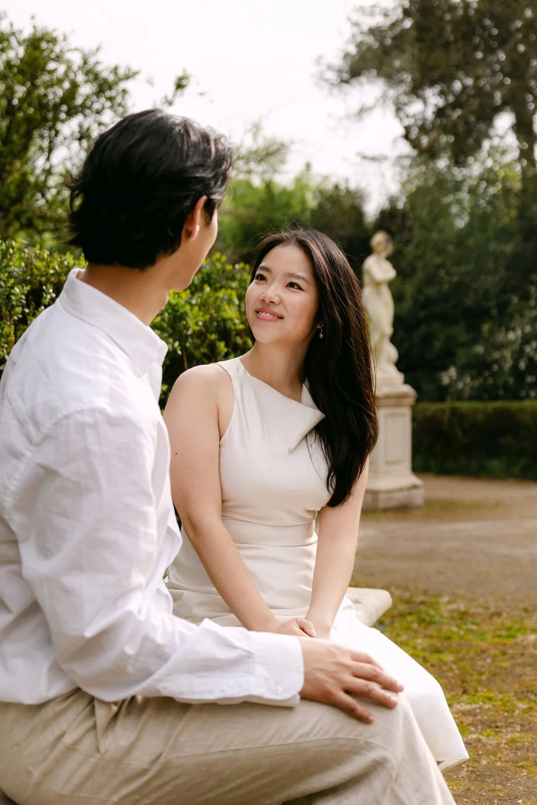 Couple sitting together in the gardens of Palácio de Queluz during engagement session.