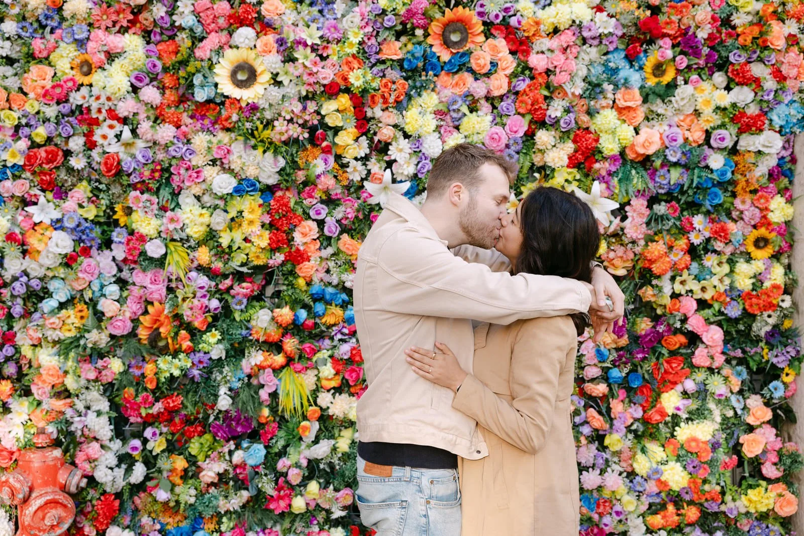 Engaged couple embracing in front of the famous flower wall near Santo António Church in Lisbon