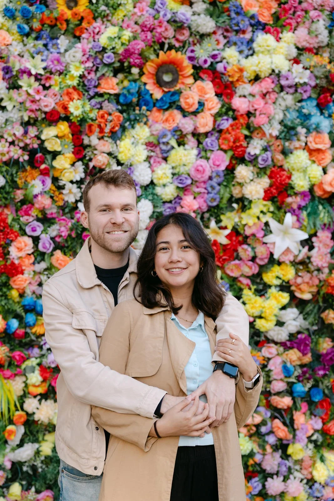 Recently engaged couple posing in front of the flower installation at Santo António Church in Lisbon
