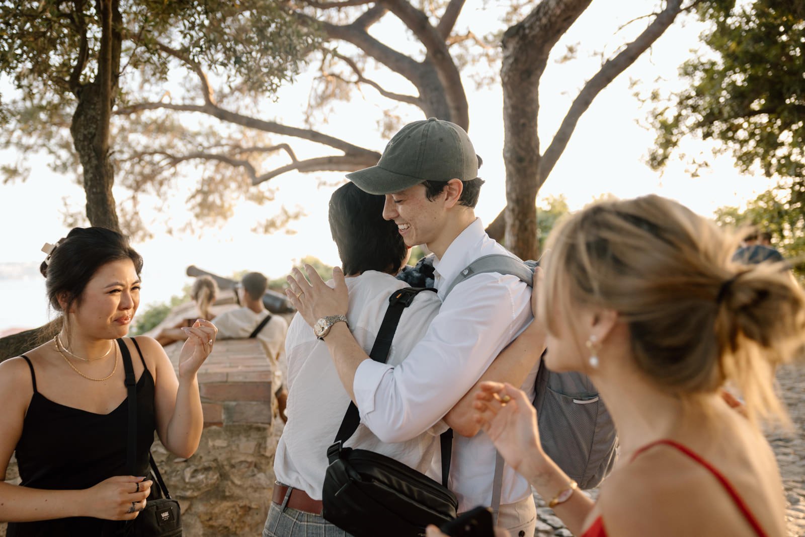 Friends congratulating a newly engaged couple after a surprise proposal at Castelo de São Jorge in Lisbon.
