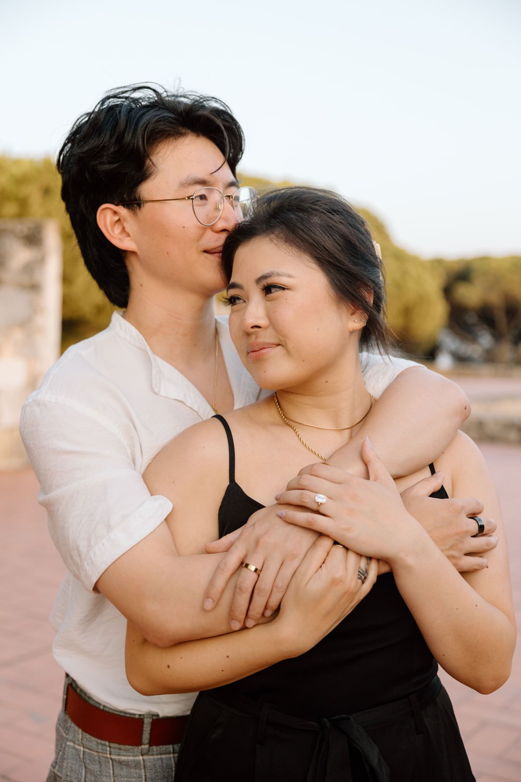 Couple embracing during a golden hour engagement photoshoot at Castelo de São Jorge in Lisbon, Portugal.