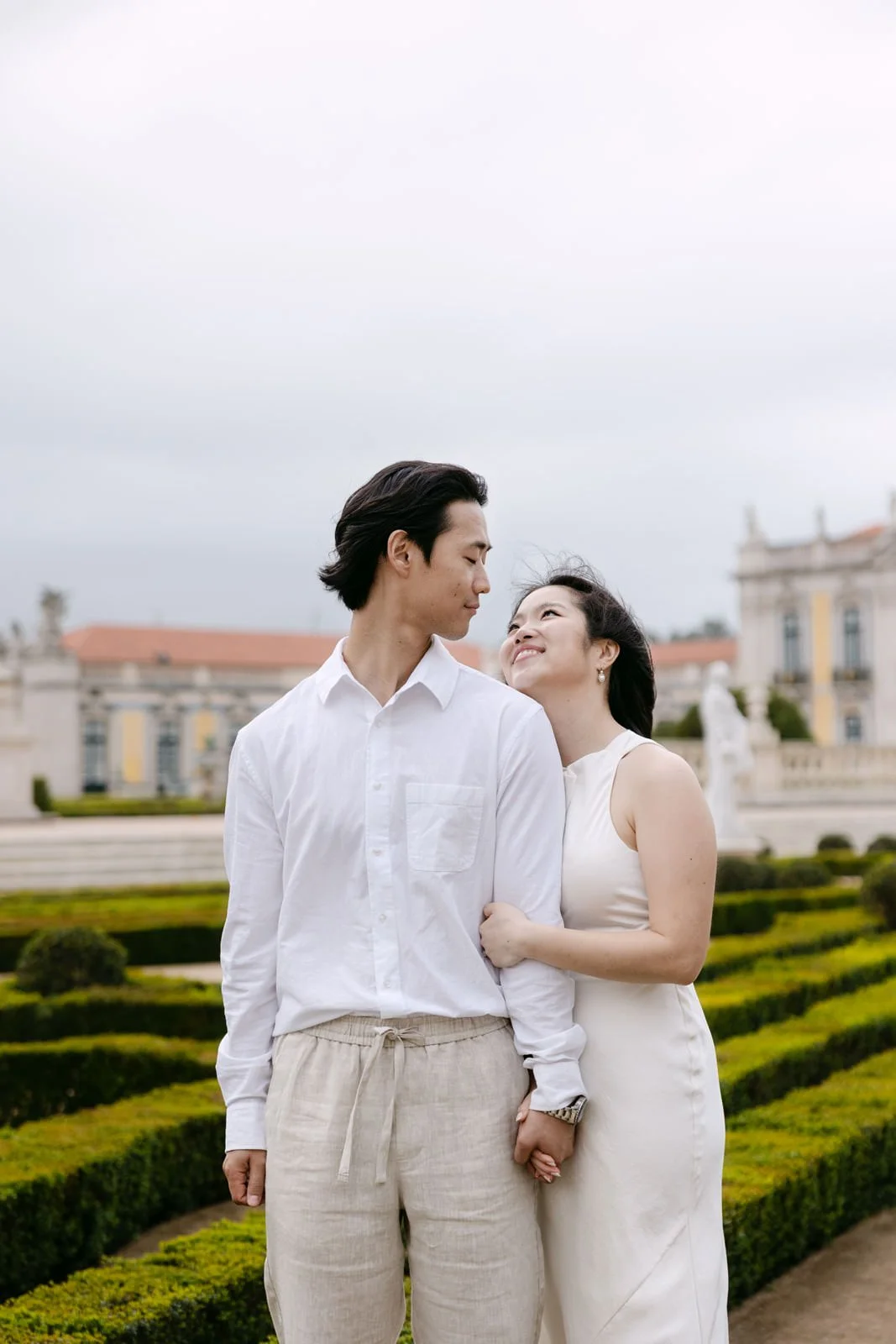 Engaged couple holding hands in the gardens of Palácio de Queluz near Lisbon.