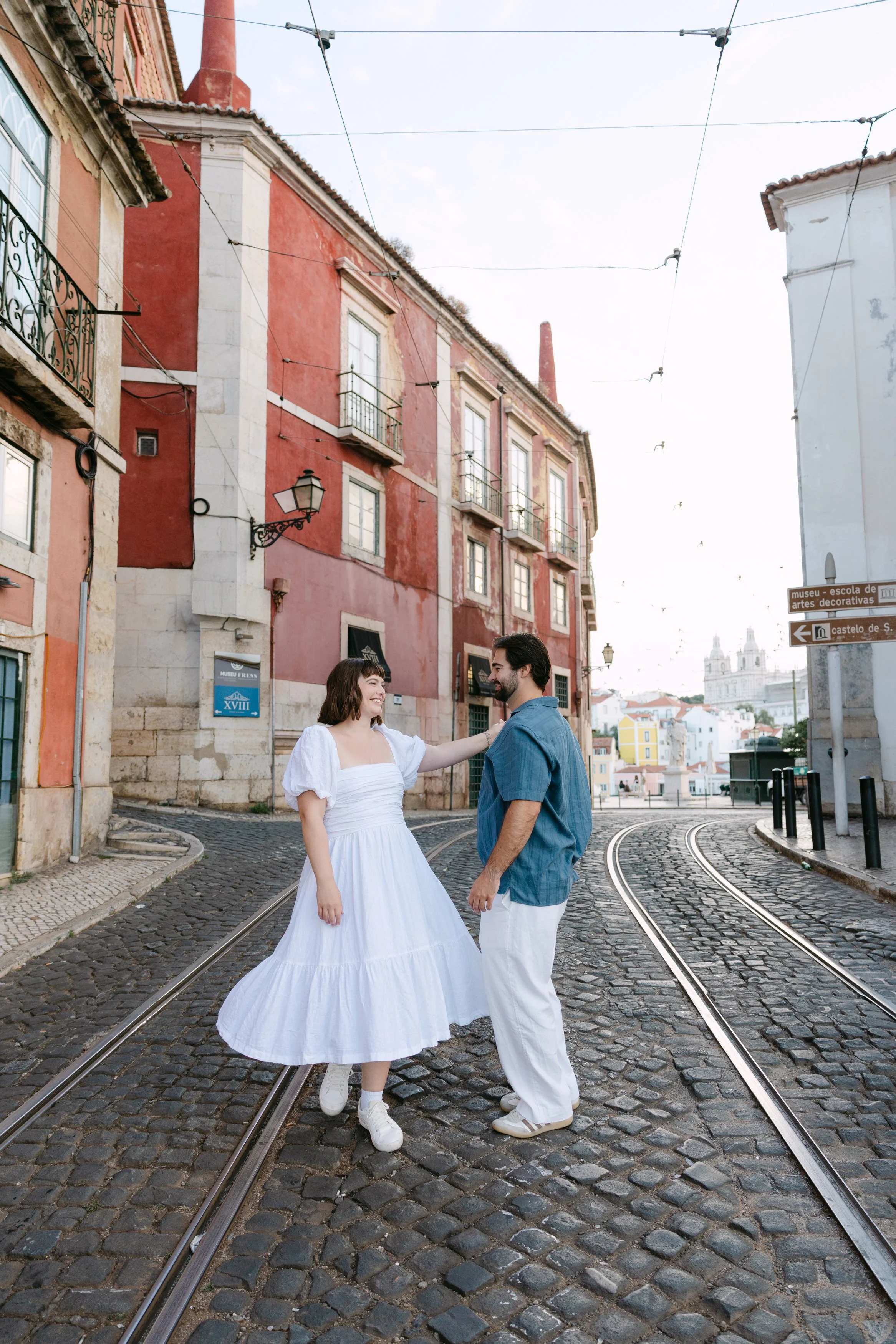 Newly engaged couple holding hands on a traditional street in Alfama after their Lisbon proposal.