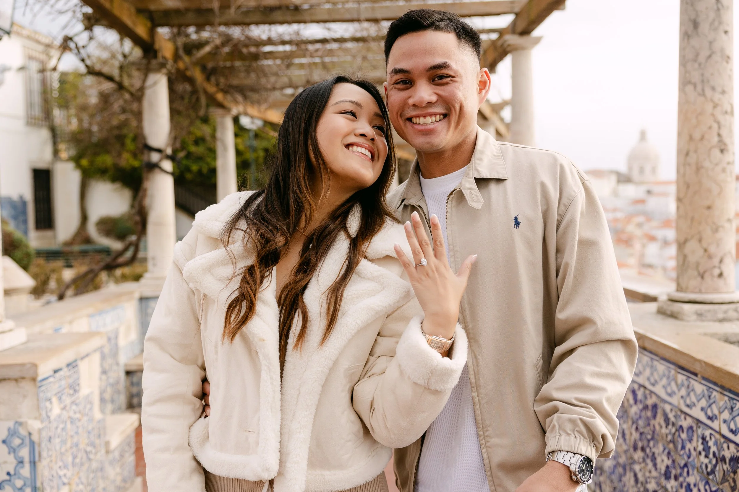 Recently engaged couple smiling at Miradouro de Santa Luzia in Lisbon Portugal