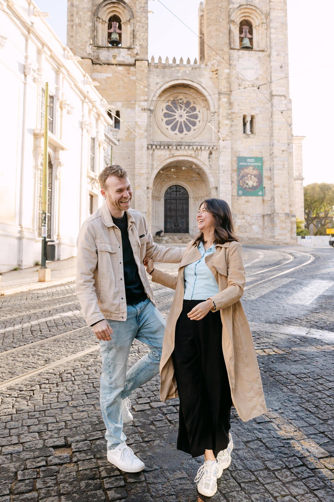 Couple laughing together outside Sé de Lisboa after a surprise proposal