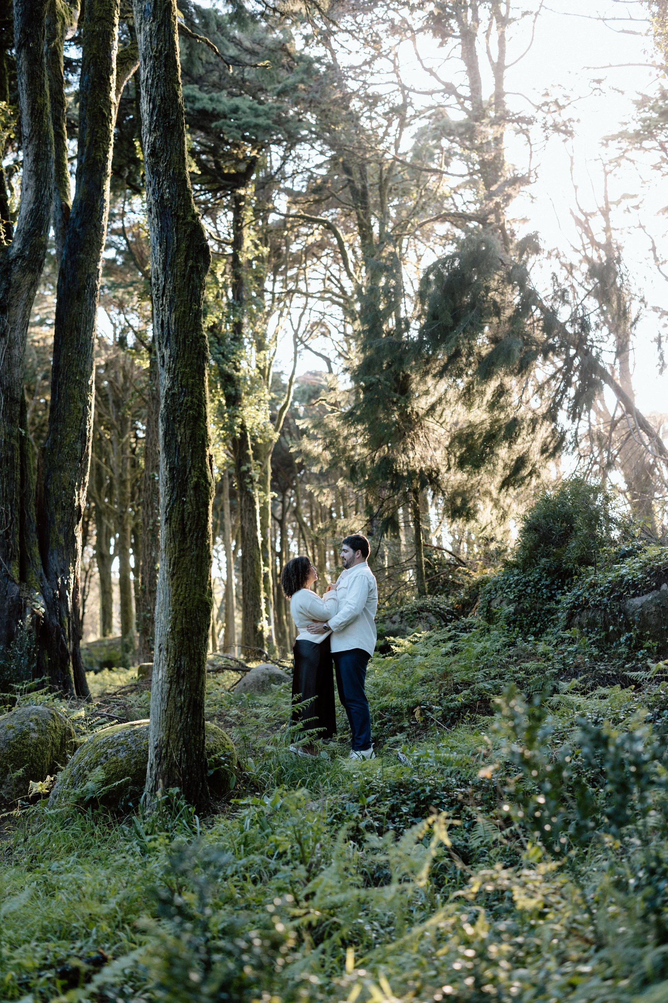 Couple standing together in forest during romantic engagement photoshoot in Portugal
