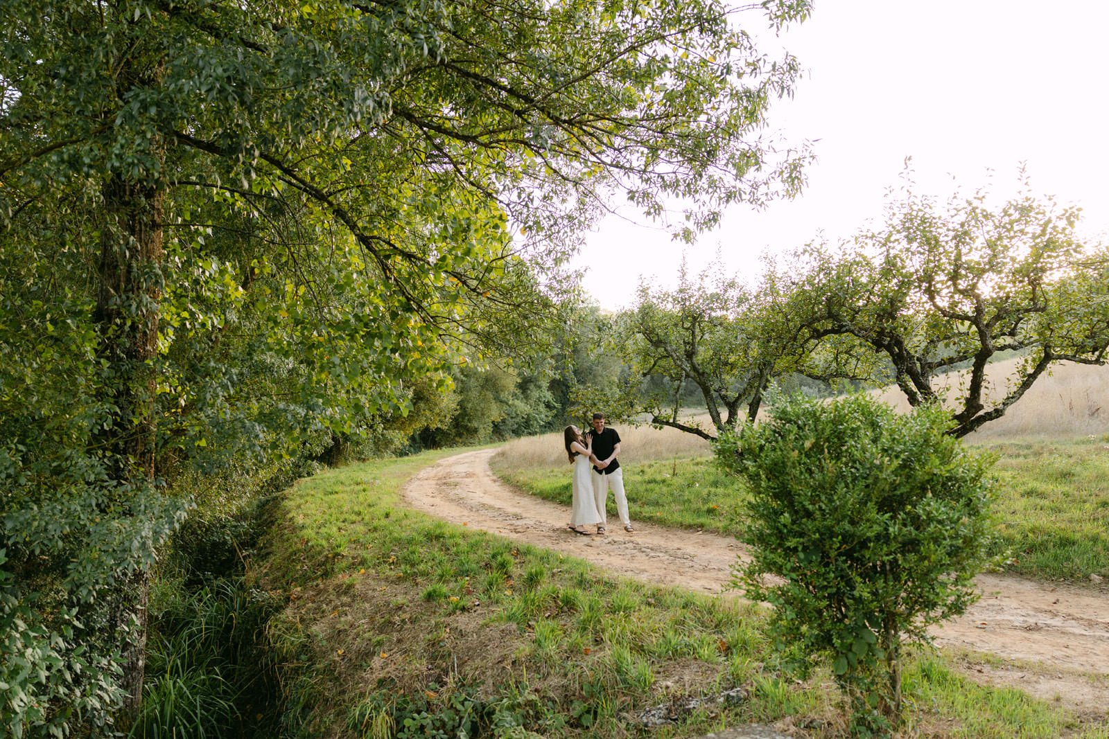 Engaged couple embracing on a quiet country path surrounded by trees and greenery at Quinta de Sant’Ana near Lisbon.