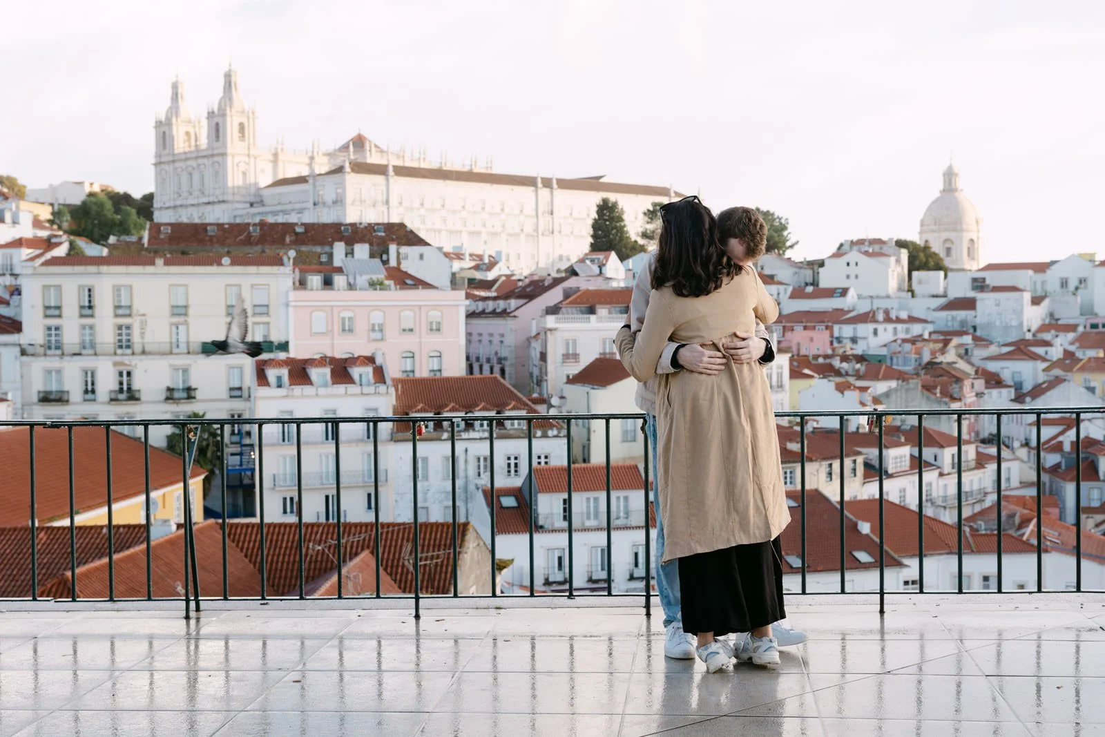 Newly engaged couple embracing at Miradouro das Portas do Sol overlooking Lisbon