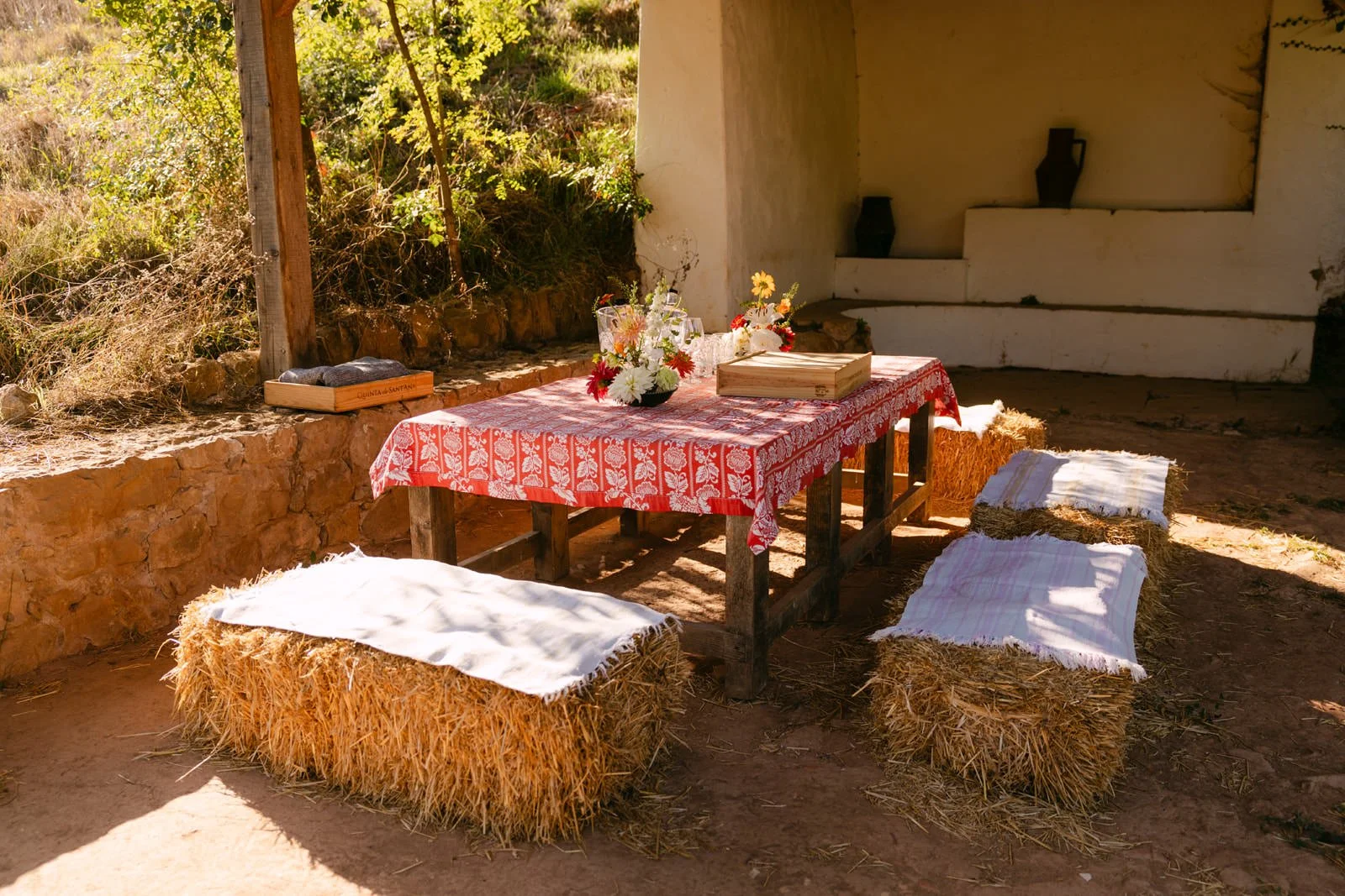 Romantic proposal picnic at Quinta de Sant’Ana with hay bale seating, flowers and a table set beneath a rustic wooden shelter.
