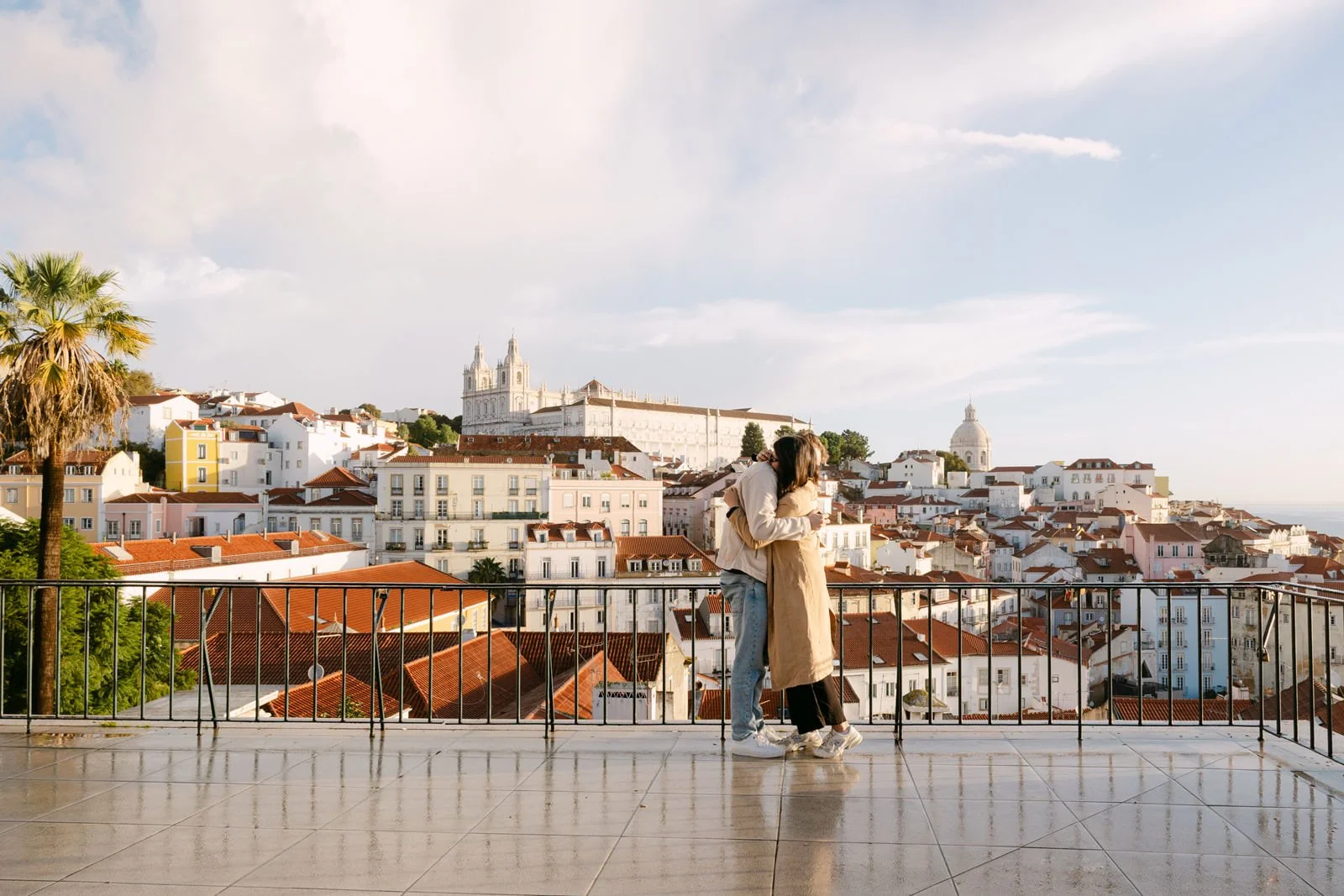 Newly engaged couple embracing at Miradouro das Portas do Sol overlooking Lisbon