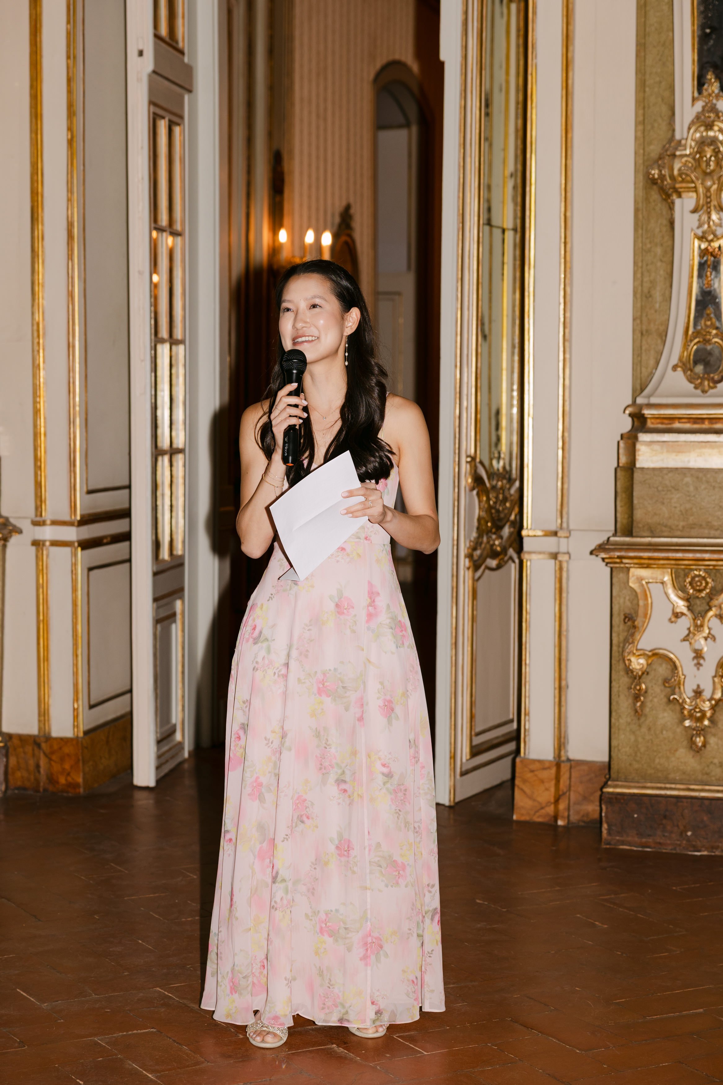 Bridesmaid in a pink floral dress smiling while giving a speech during the wedding reception at Palácio Nacional de Queluz.