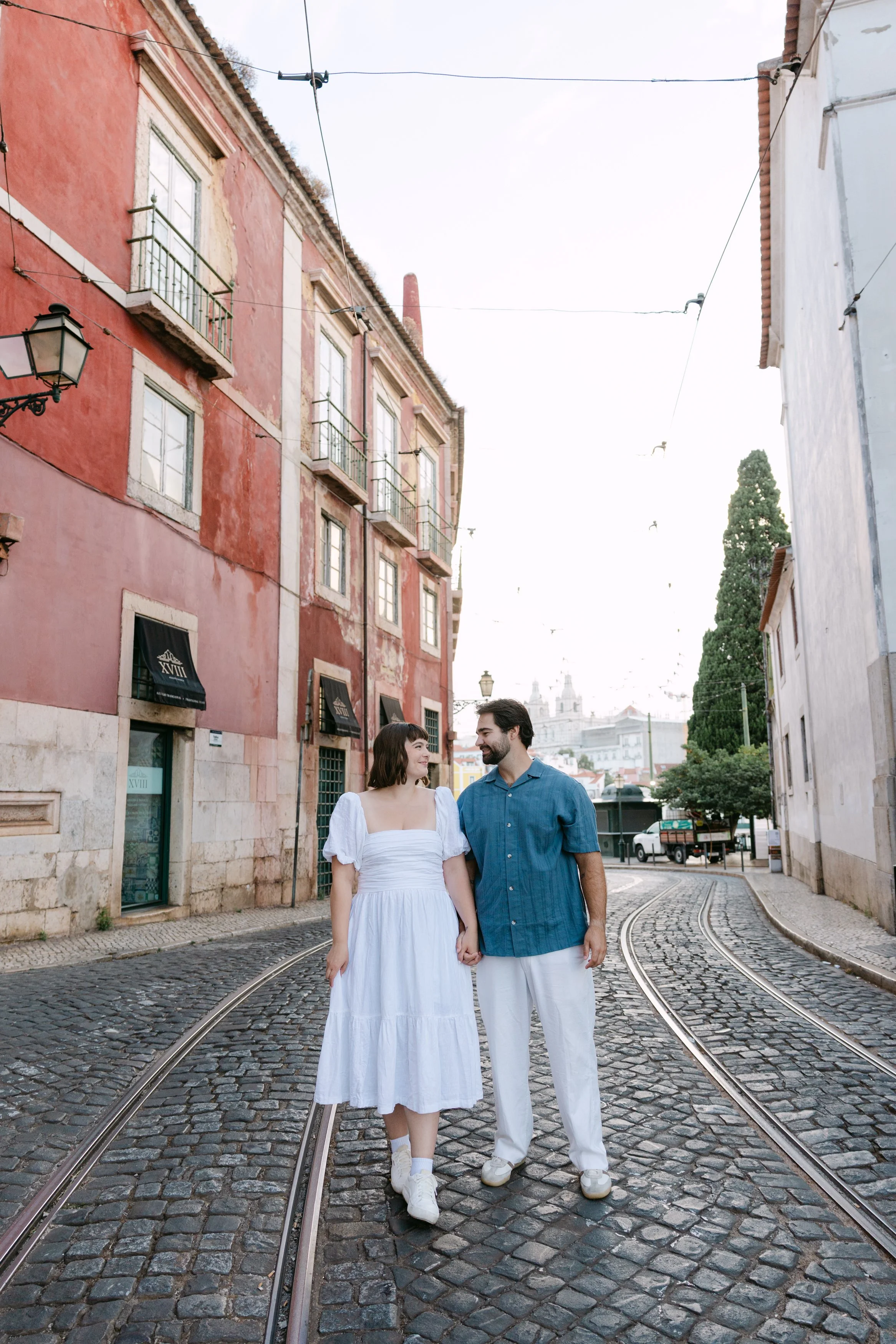 Newly engaged couple walking together through the colourful streets of Alfama in Lisbon.