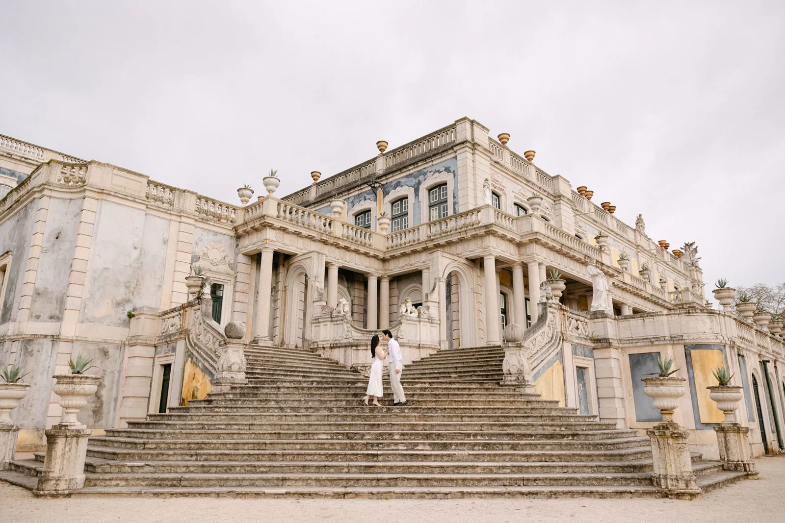 Wide portrait of engaged couple on the grand staircase of Palácio de Queluz.