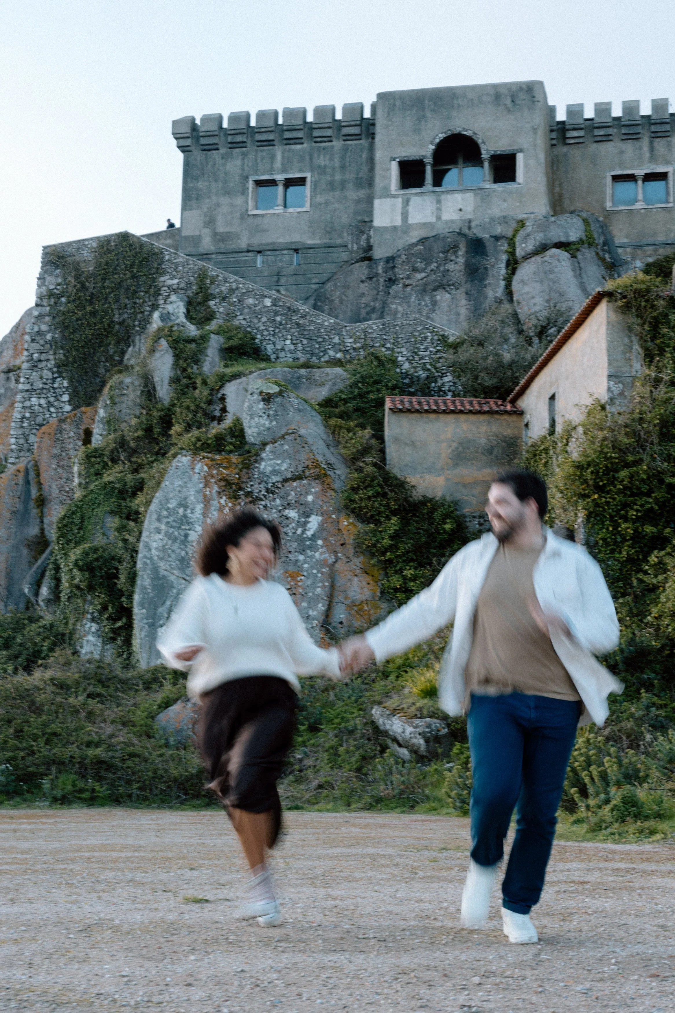 Couple running together near Santuário da Peninha during engagement session in Sintra