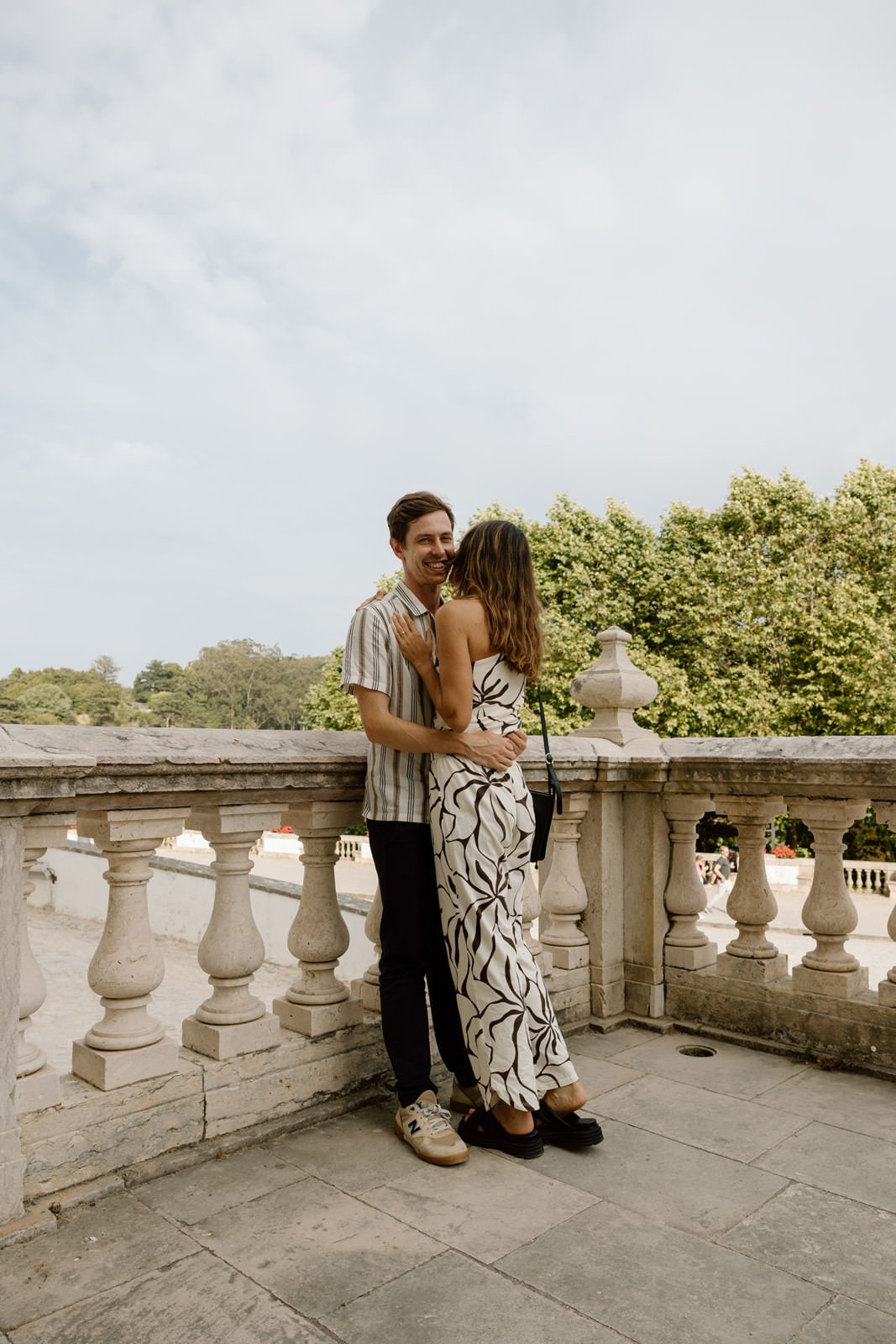 Engaged couple embracing on a balcony at Palácio Nacional de Sintra during a romantic engagement session in Portugal.
