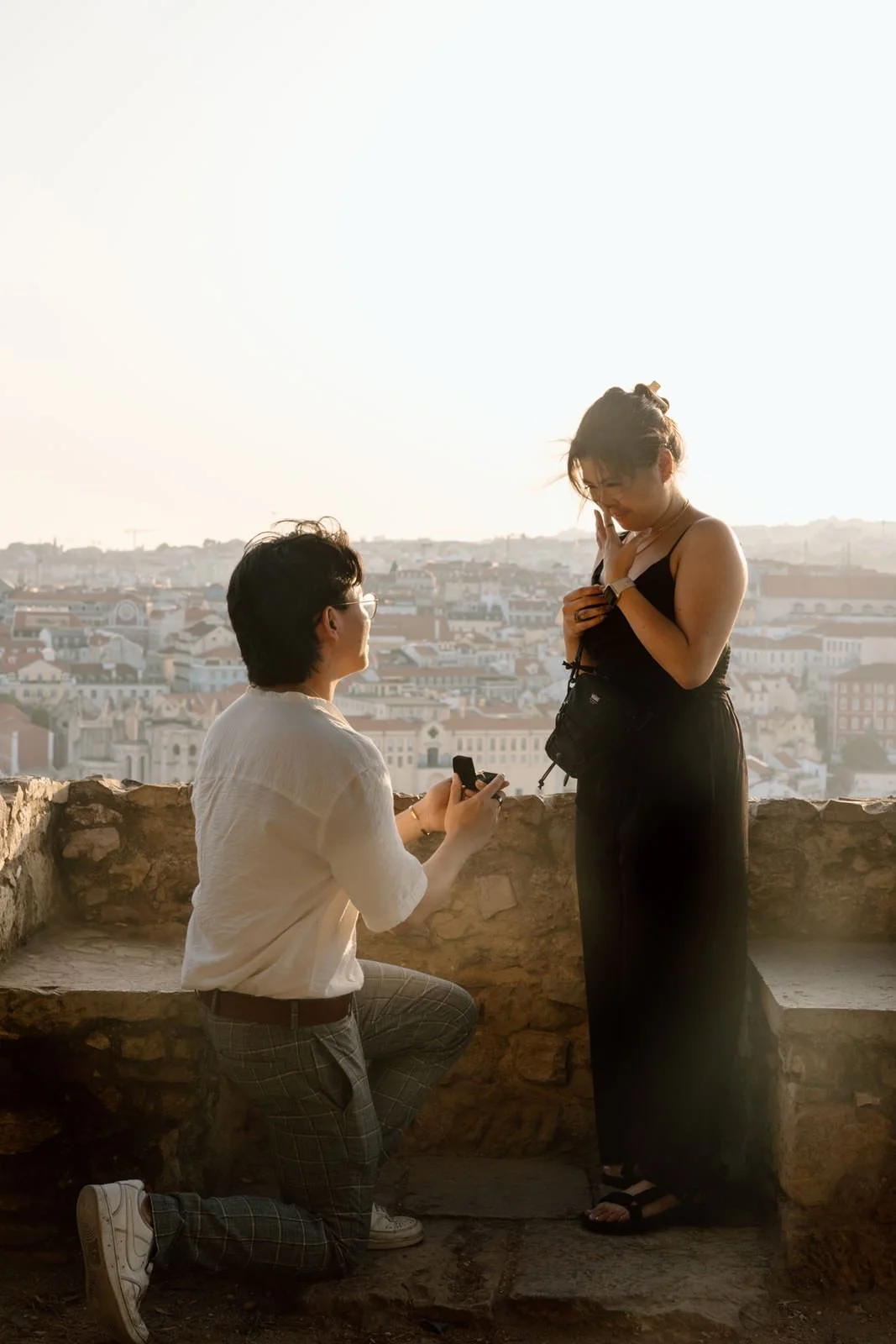 Couple getting engaged during a surprise proposal at Castelo de São Jorge in Lisbon, Portugal.