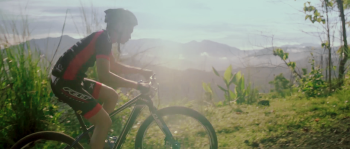 A mountain biker scales a grassy hillside in the Philippines