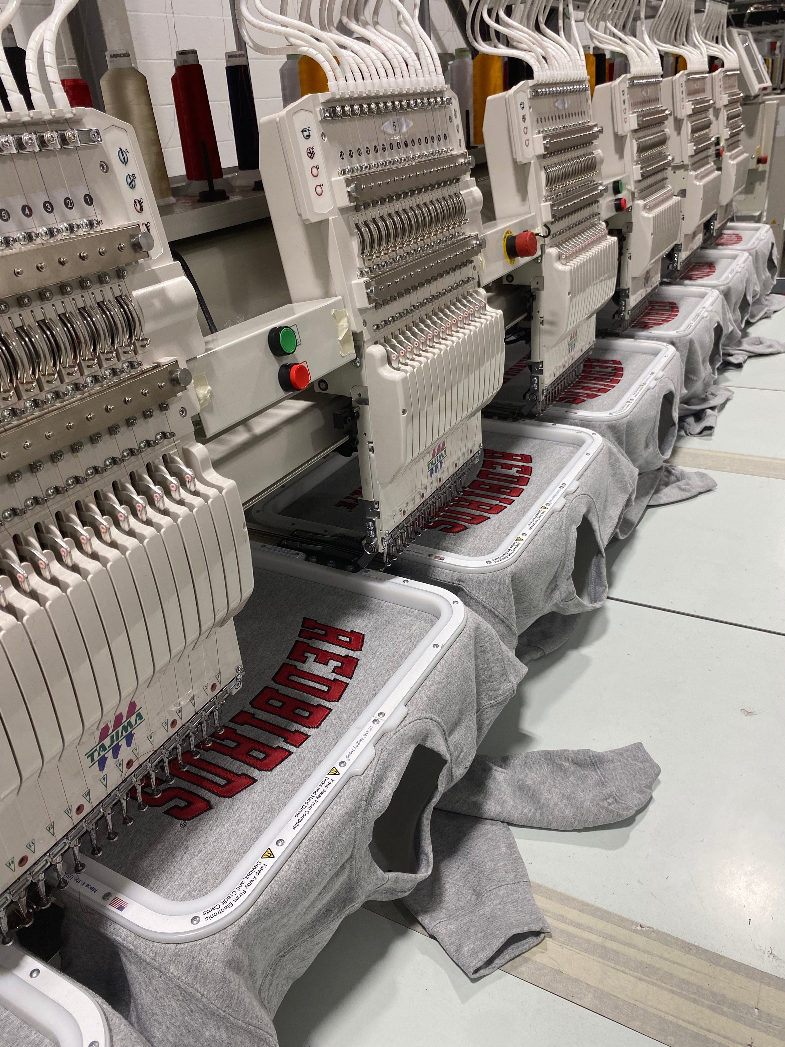 Embroidery machines stitching school mascot name on custom crewneck sweater