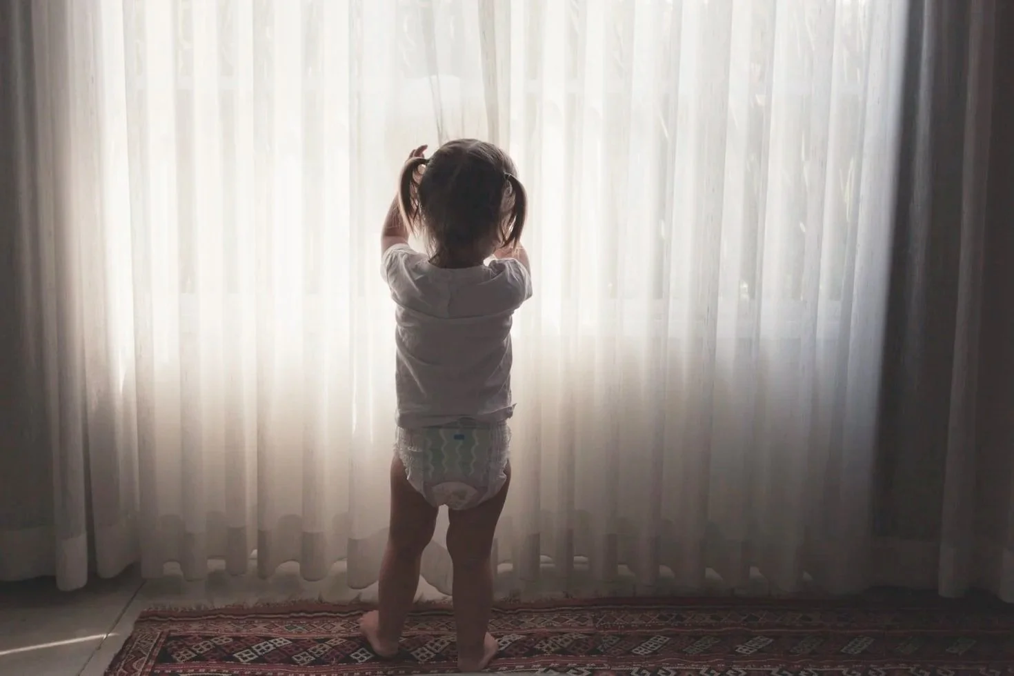 toddler in diapers hiding to go poop in the curtains.jpg