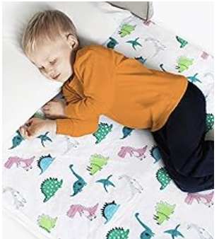 Child sleeping on a bed with a mattress protector and pillow, wearing pajamas.