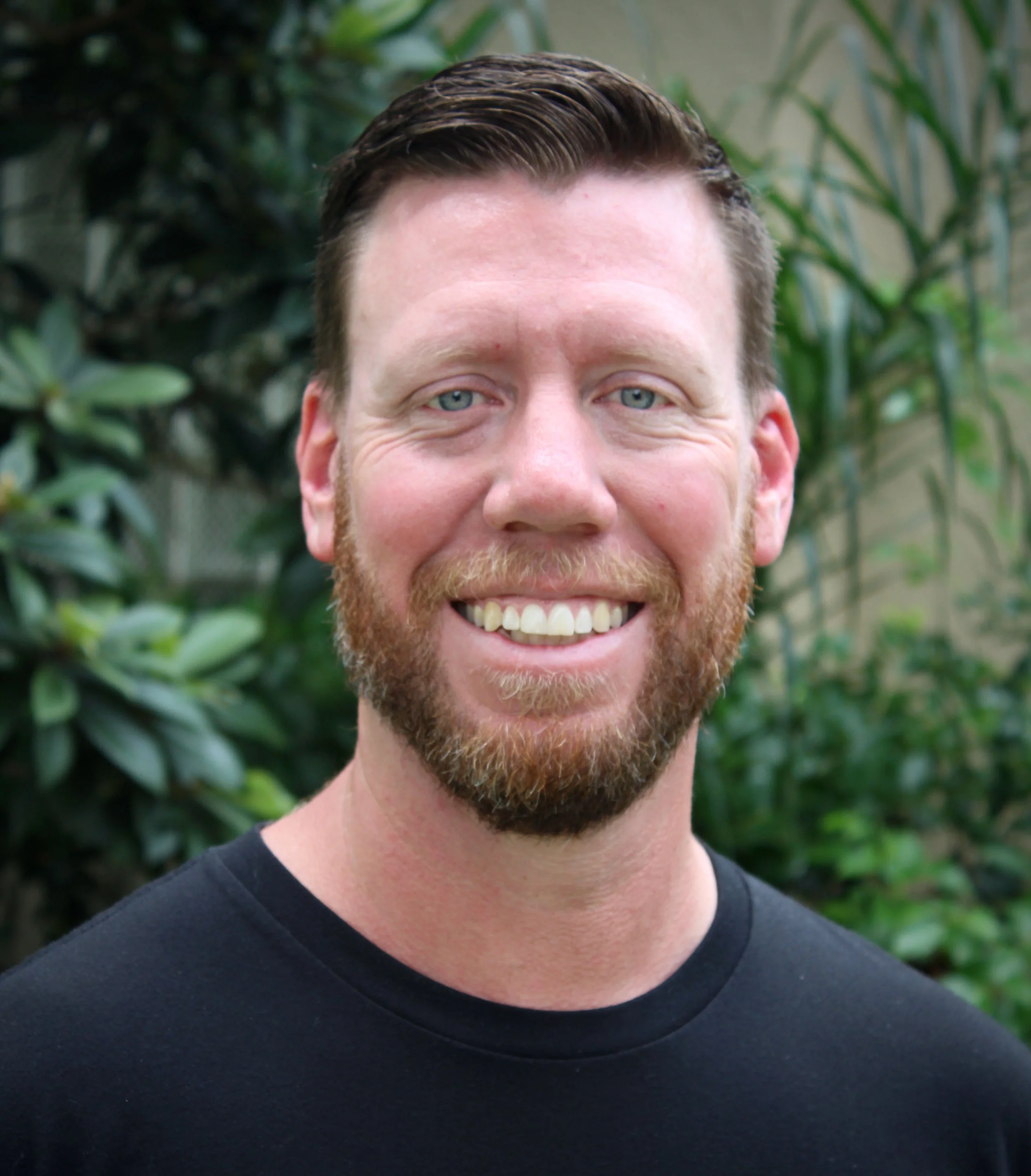 Smiling man with a beard and a black t-shirt