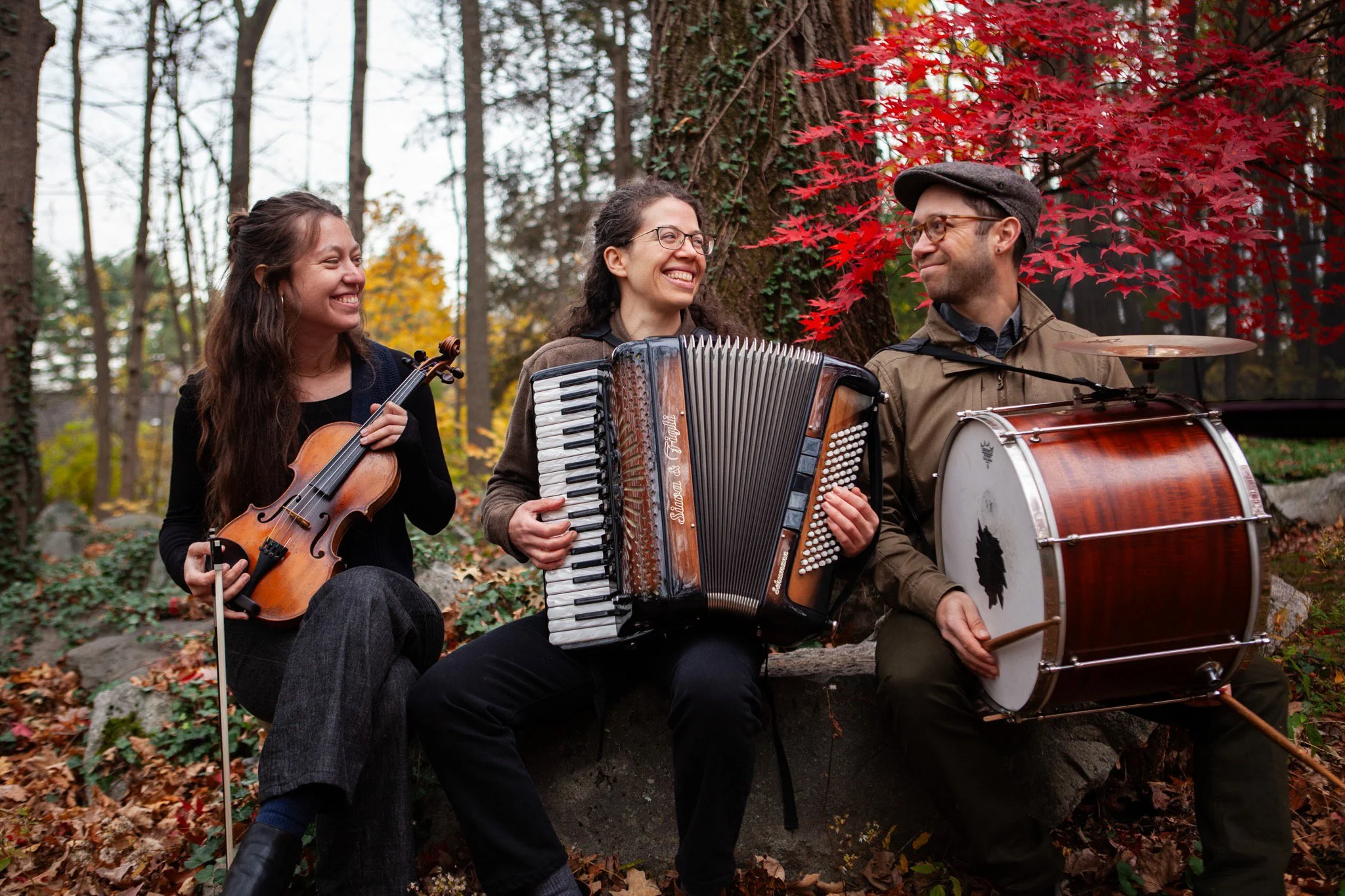 A Glezele Tey klezmer trio with their instruments in the woods