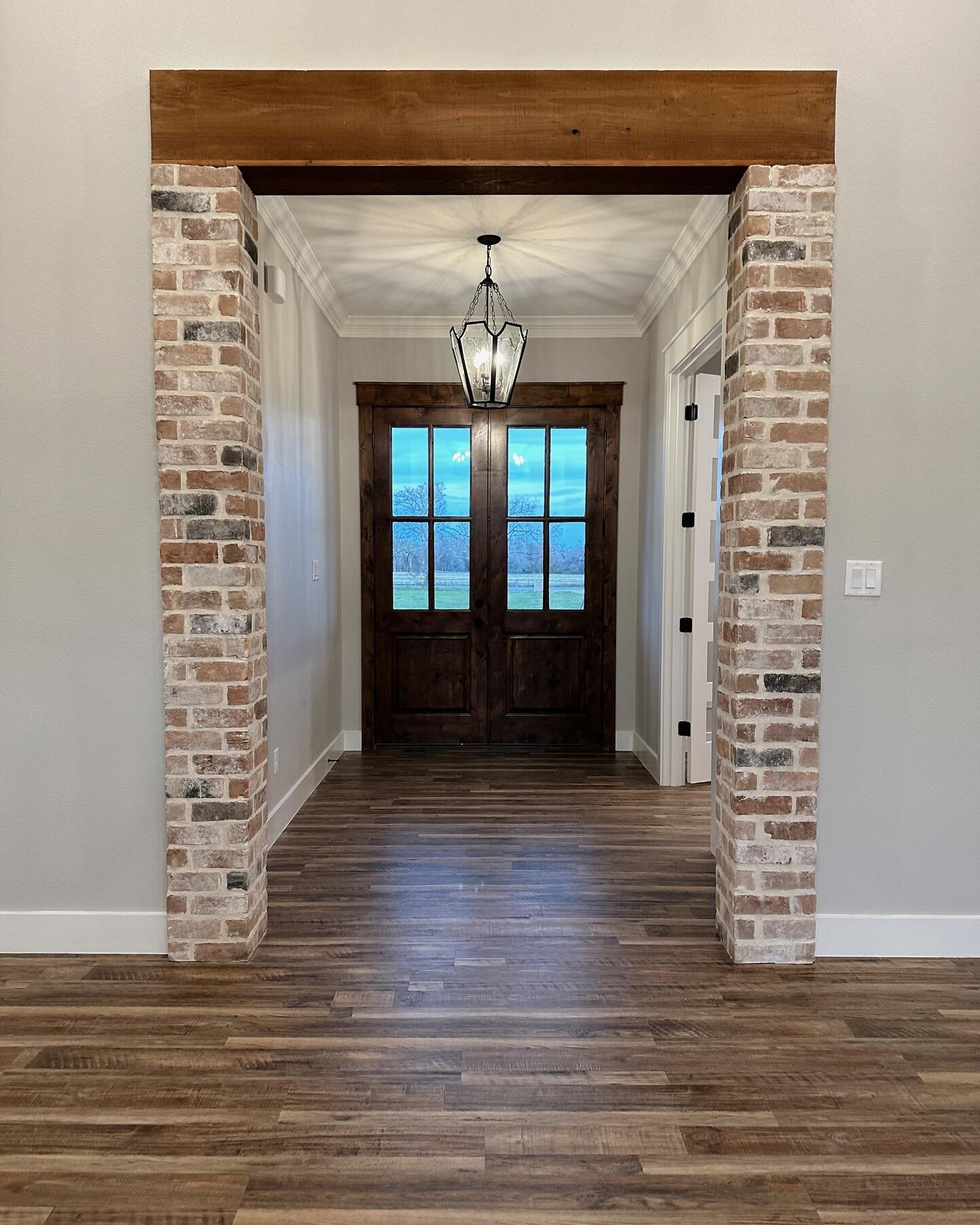 Step into our latest custom open-concept dream home featuring a stunning kitchen with a brick backsplash, a sleek butcher top island, and custom oak French doors. 🏡