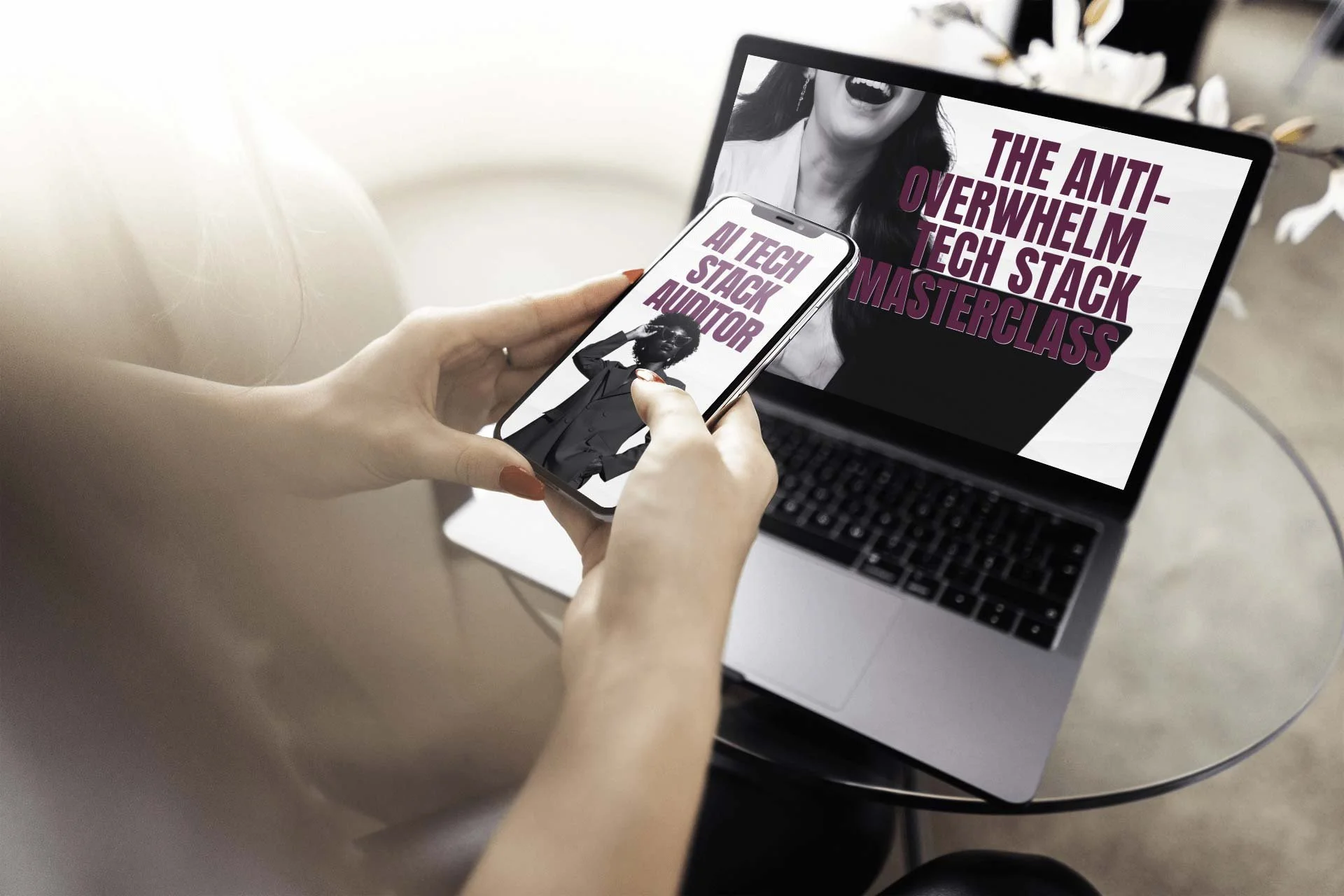 Person holding a smartphone displaying text about an AI tech masterclass, with a laptop open on a glass table showing related promotional graphics