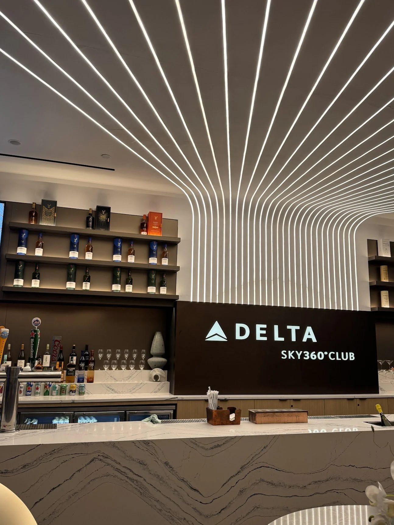 Marble bar beneath a ceiling of sweeping white light in the Delta Sky360 Club at Citi Field