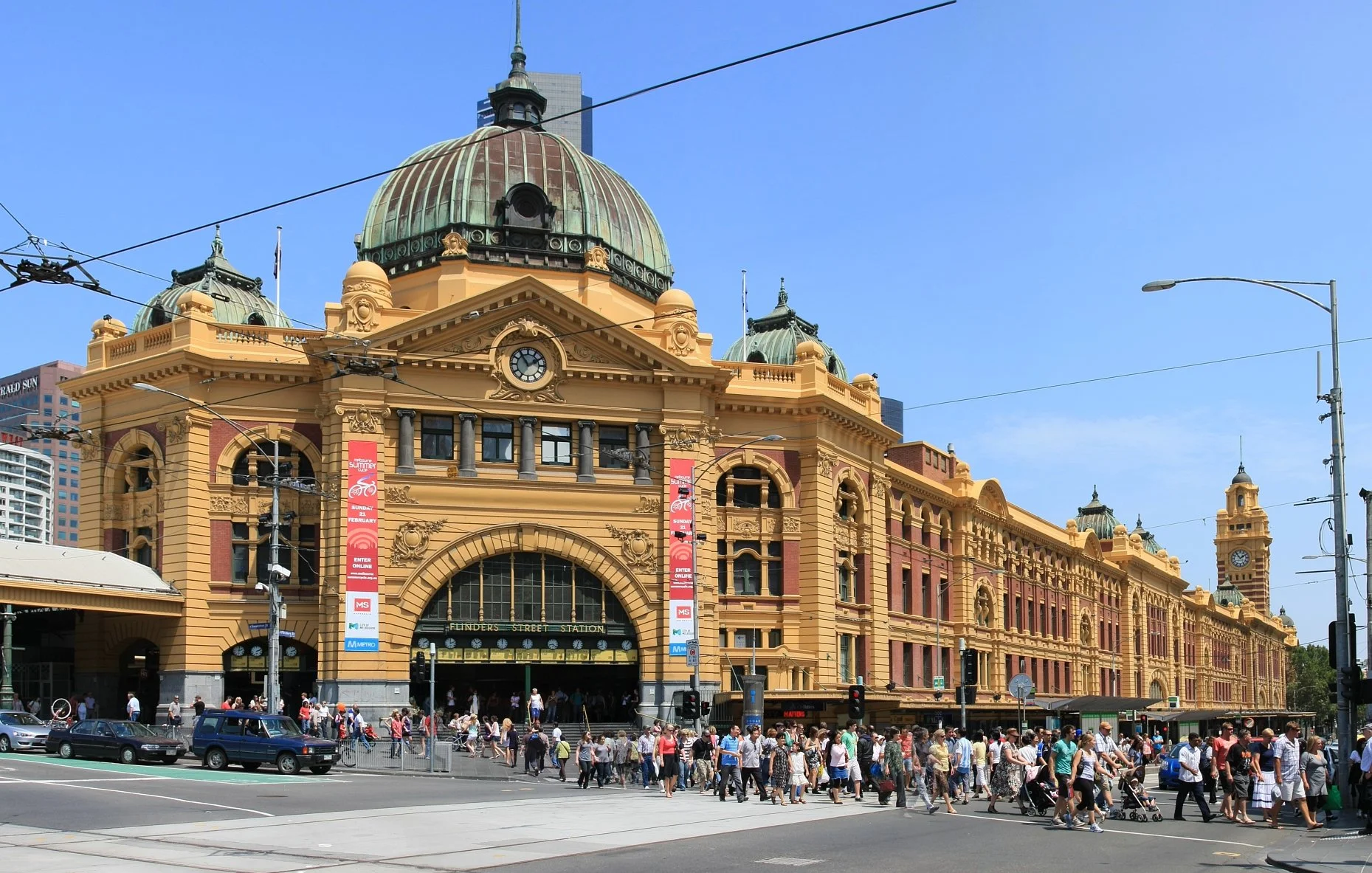 Wide angle shot of Flinders Street station with pedestrians crossing the road.