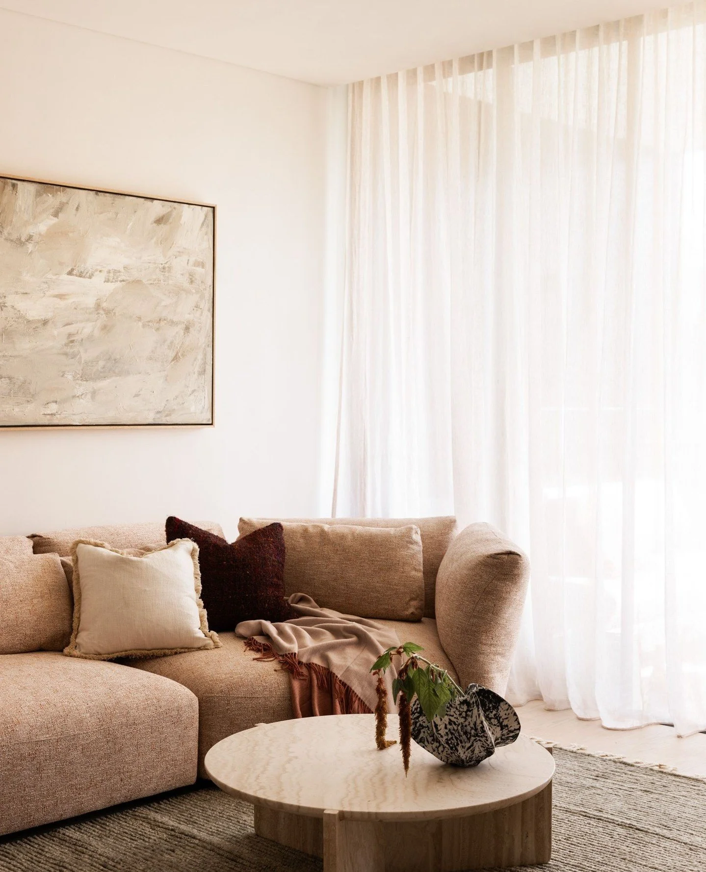In the living room, the palette softens into warm neutrals and tactile comfort.⁠
⁠
Rounded edges, textural fabrics and a play of light all contribute to a sense of serenity. This is where the home slows down &mdash; a place to unwind, connect and sim