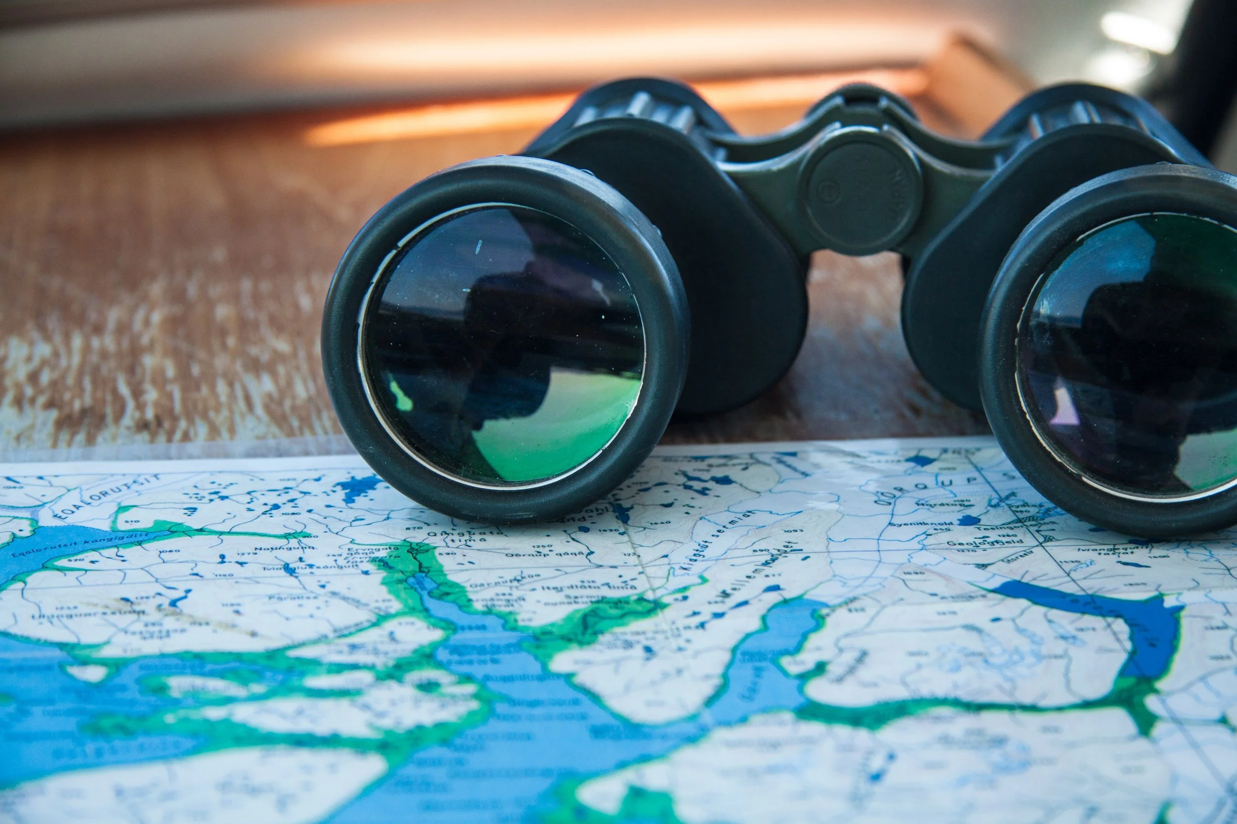 Ein Fernglas liegt auf einer Karte, die Wasserwege und Seen zeigt.
