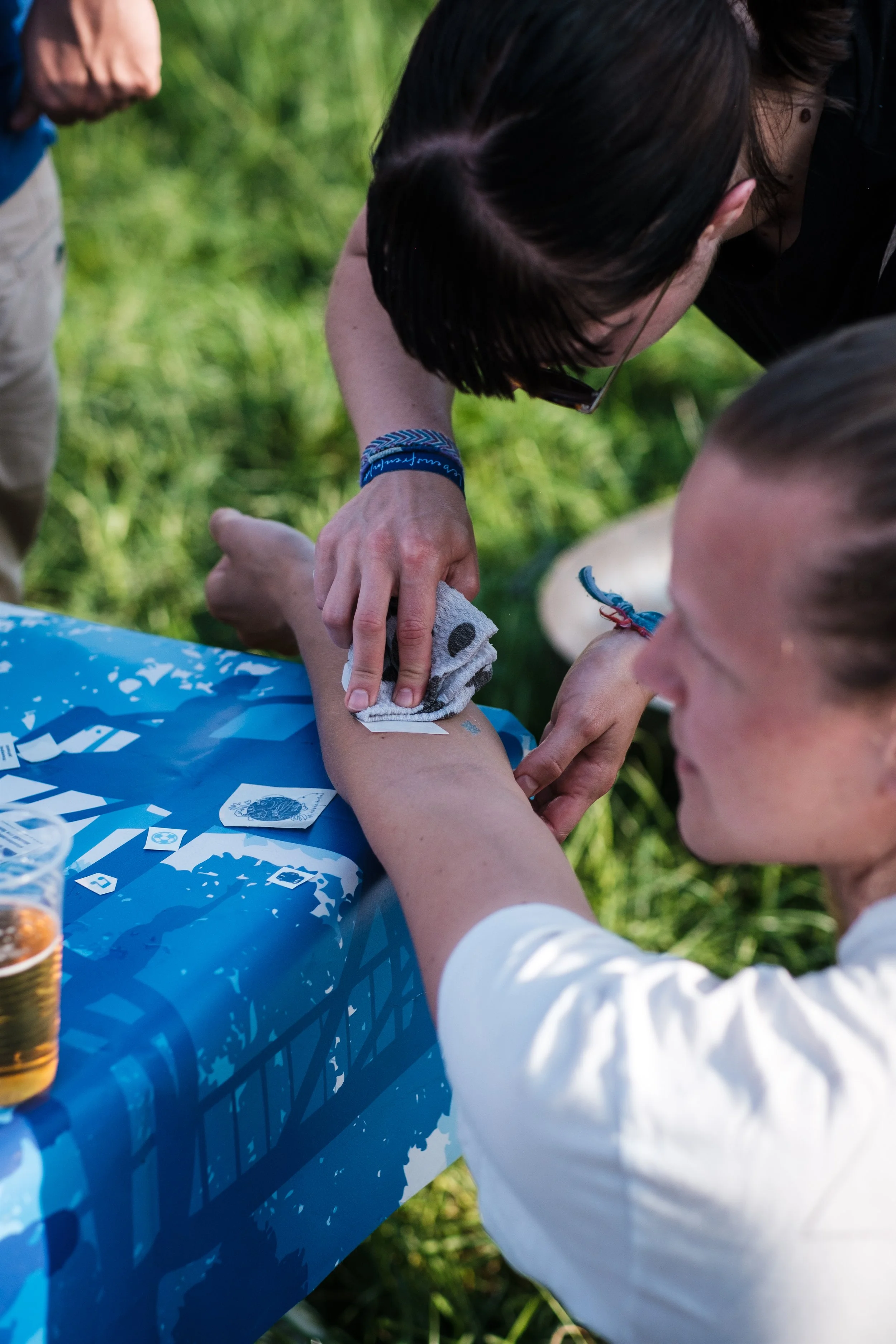Eine Person wird in einer Outdoor-Umgebung versehentlich mit einem Messer in den Arm geschnitten. Eine andere Person behandelt die Wunde mit einem Tuch.