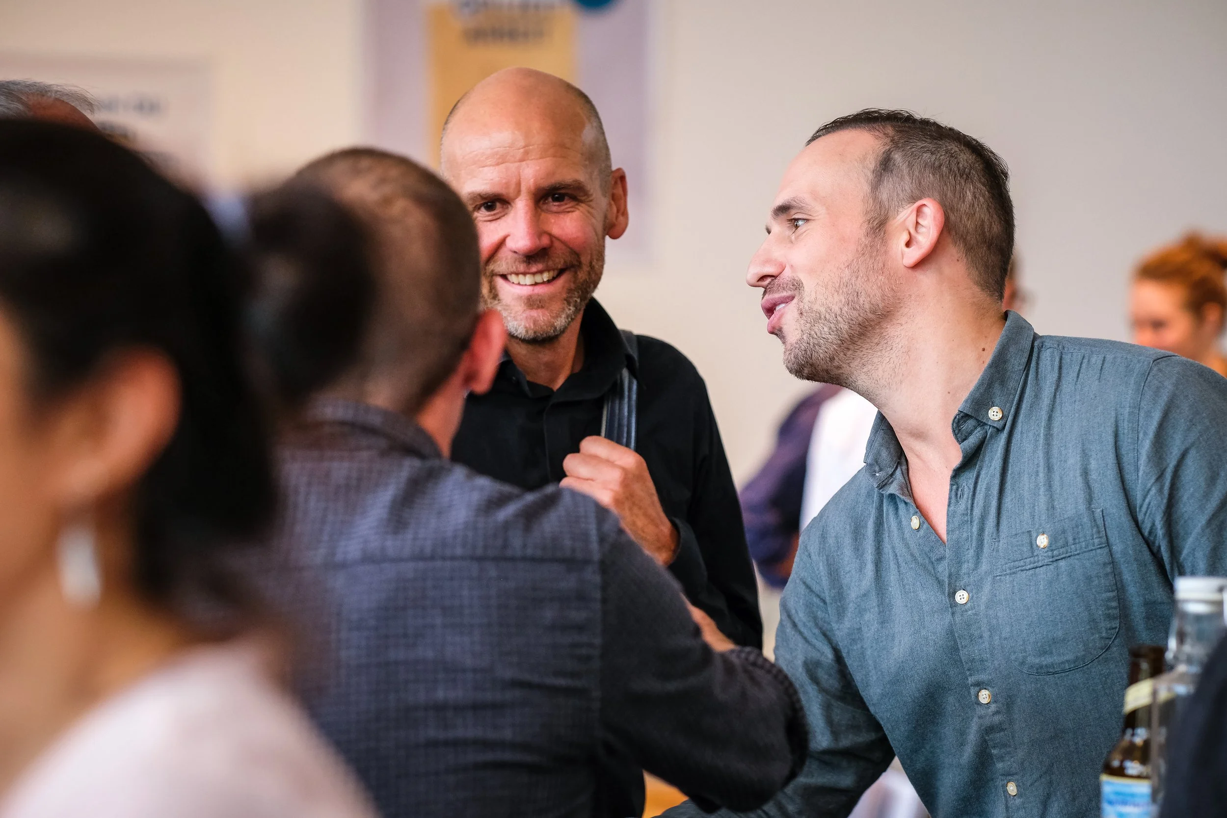 Menschen beim Gespräch bei einem Treffen oder Event, lächelnd und im Gespräch.