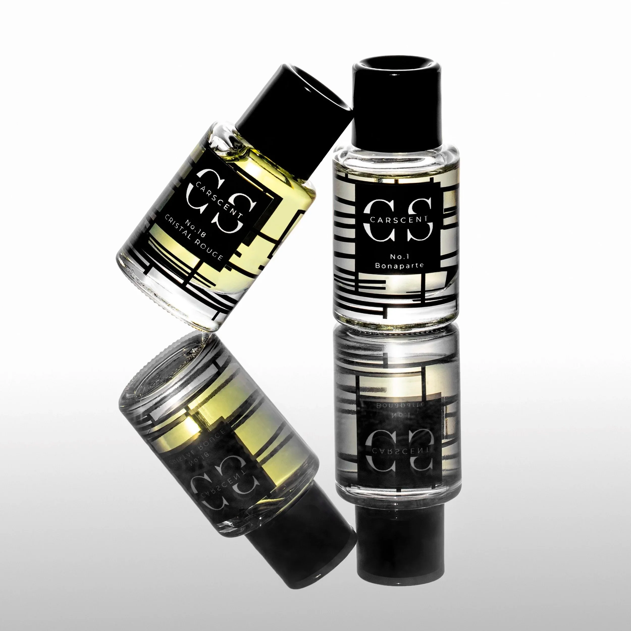 Two bottles of CarScent perfume on a reflective surface, one standing upright and the other tilted, with black and white geometric labels.