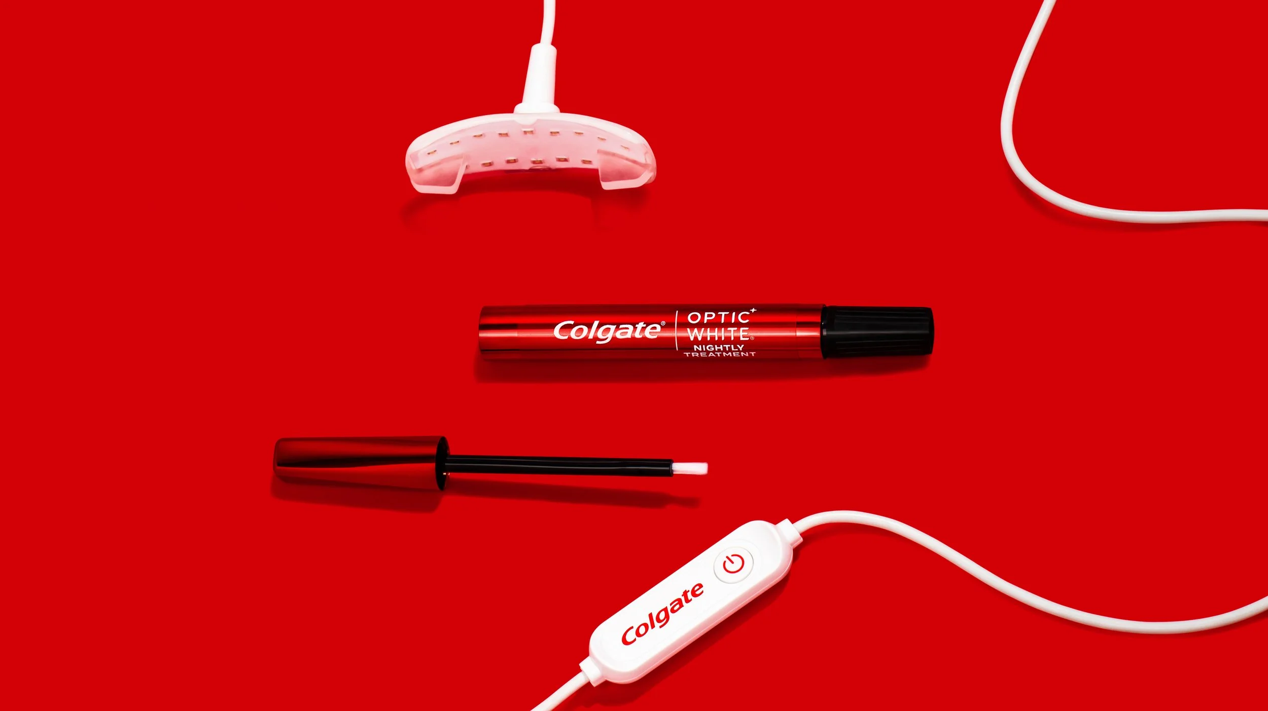 Collage of dental care items including a toothbrush, dental whitening pen, a white device with a power button, and electric wires, all set on a bright red background.