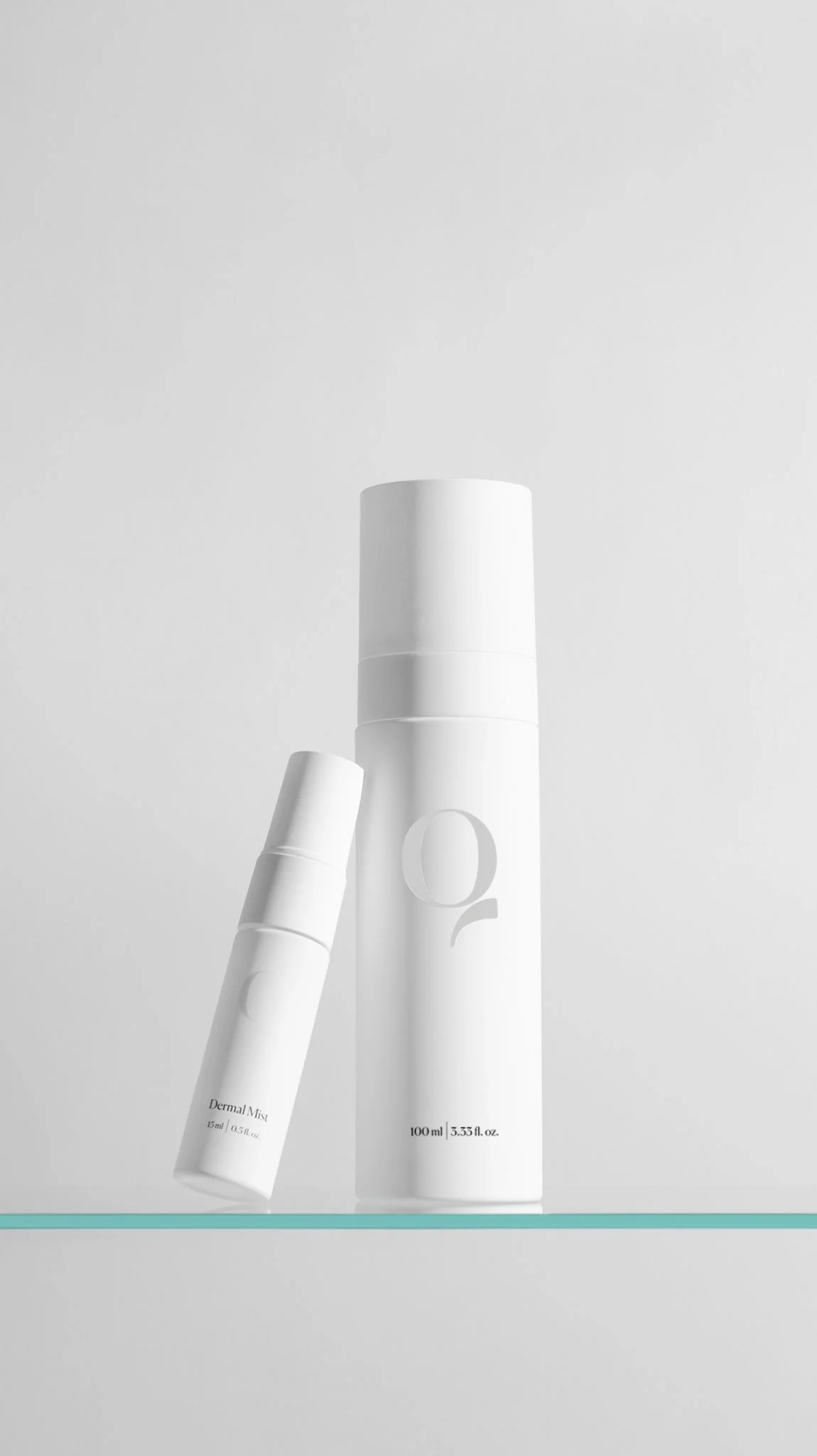 Two white skincare spray bottles, one taller and larger, the other smaller and tilted, on a light surface with a simple background.