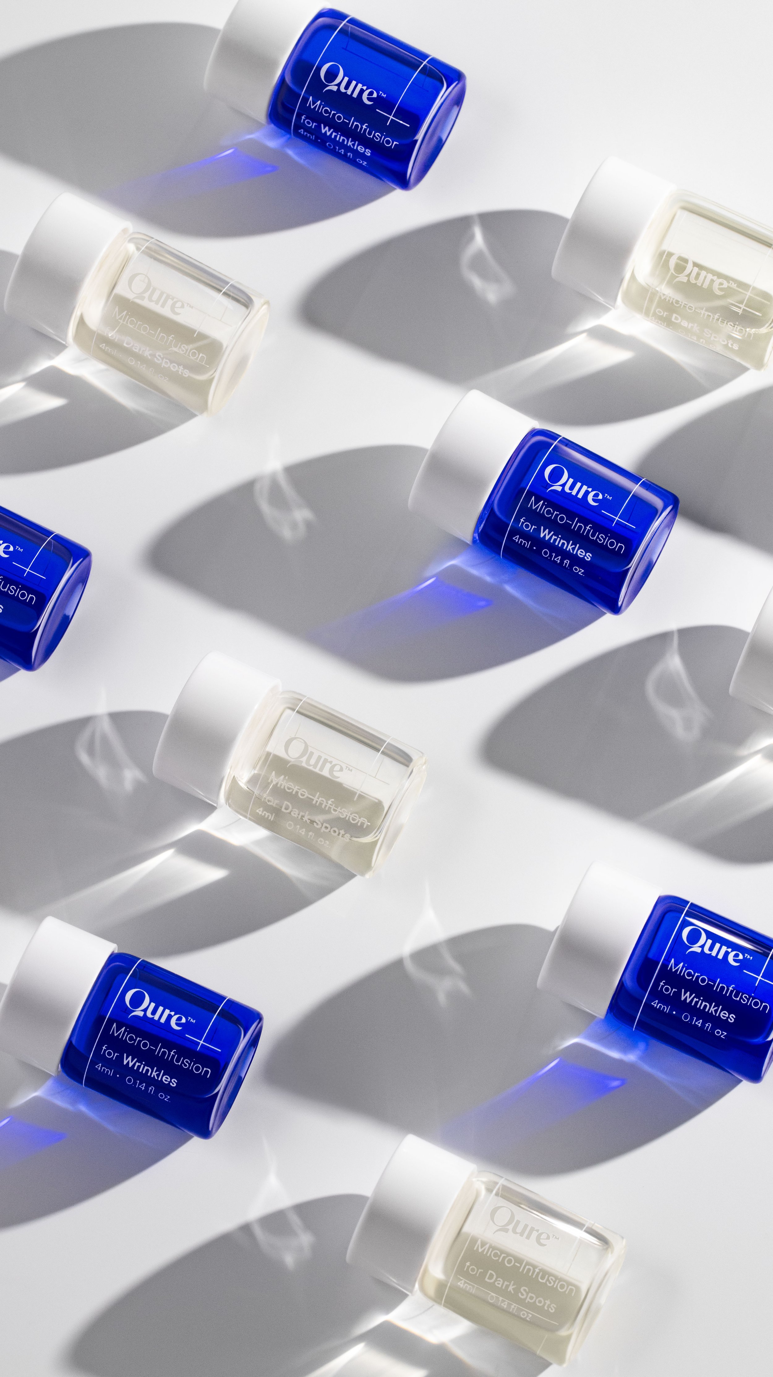 Multiple bottles of Qure Micro-Infusion for Wrinkles and Dark Spots on a white surface, casting shadows.